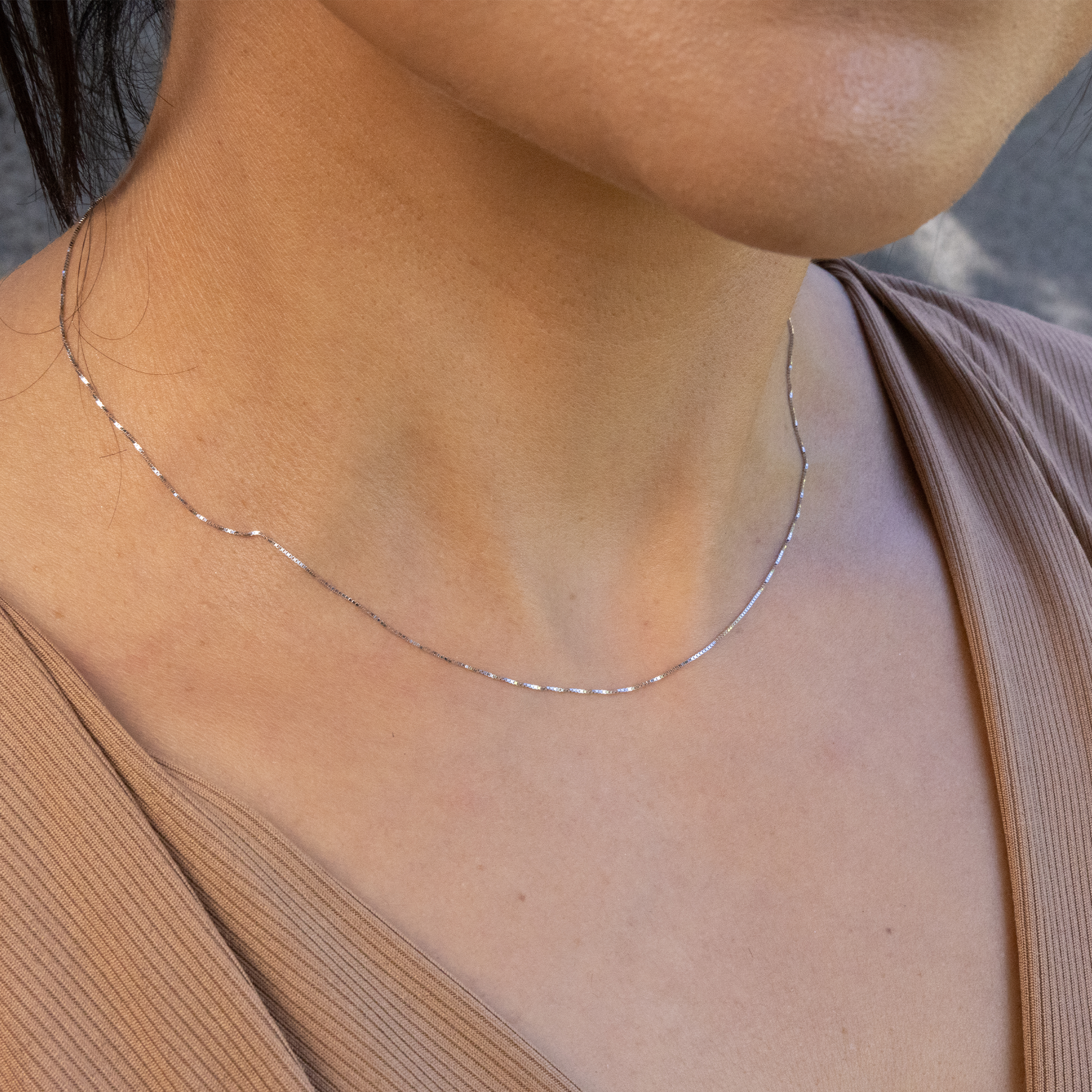 Close up of 0.6mm Box Chain in 10k White Gold on a woman's neckline