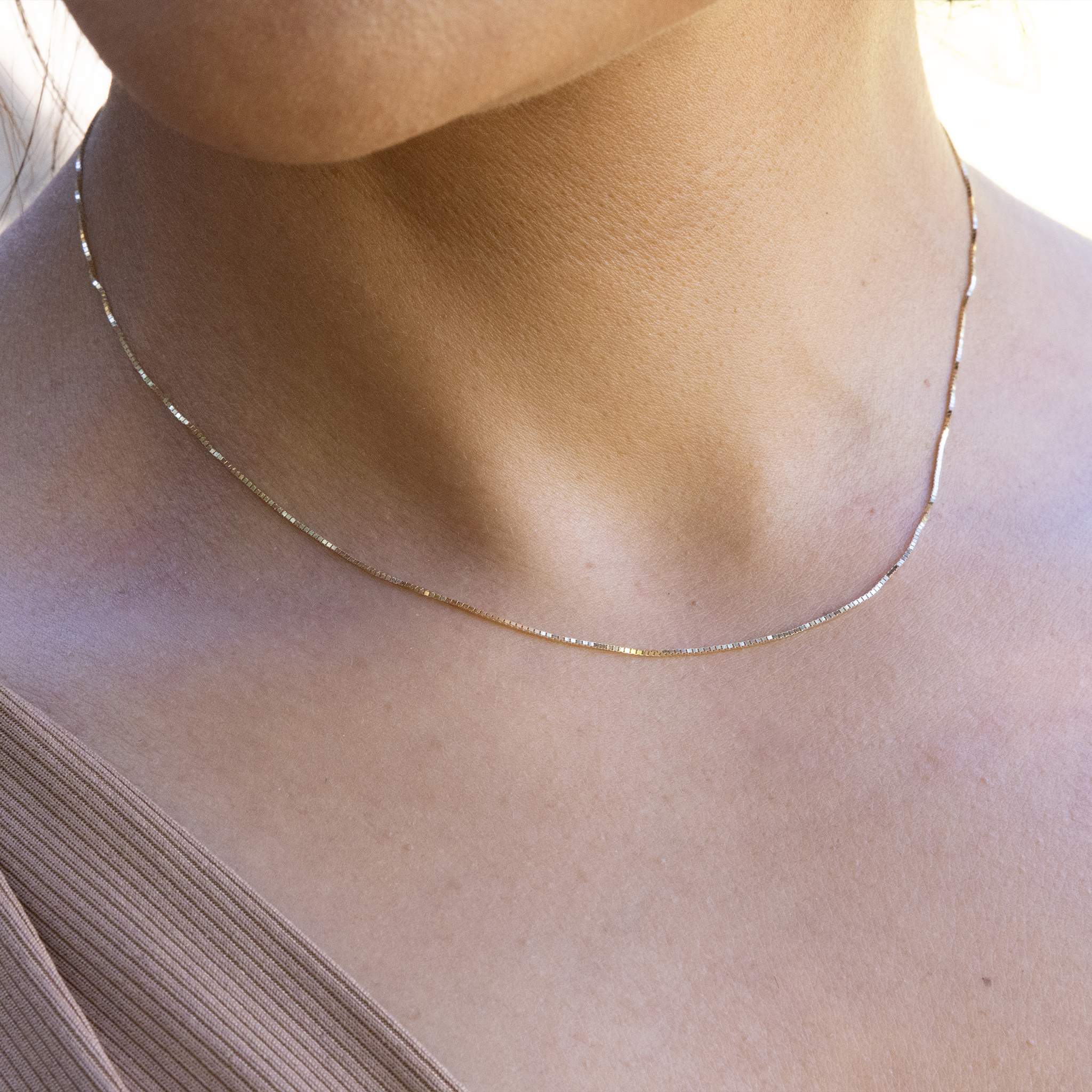 Close up of 0.8mm Venetian Box Chain in Gold on woman's neckline
