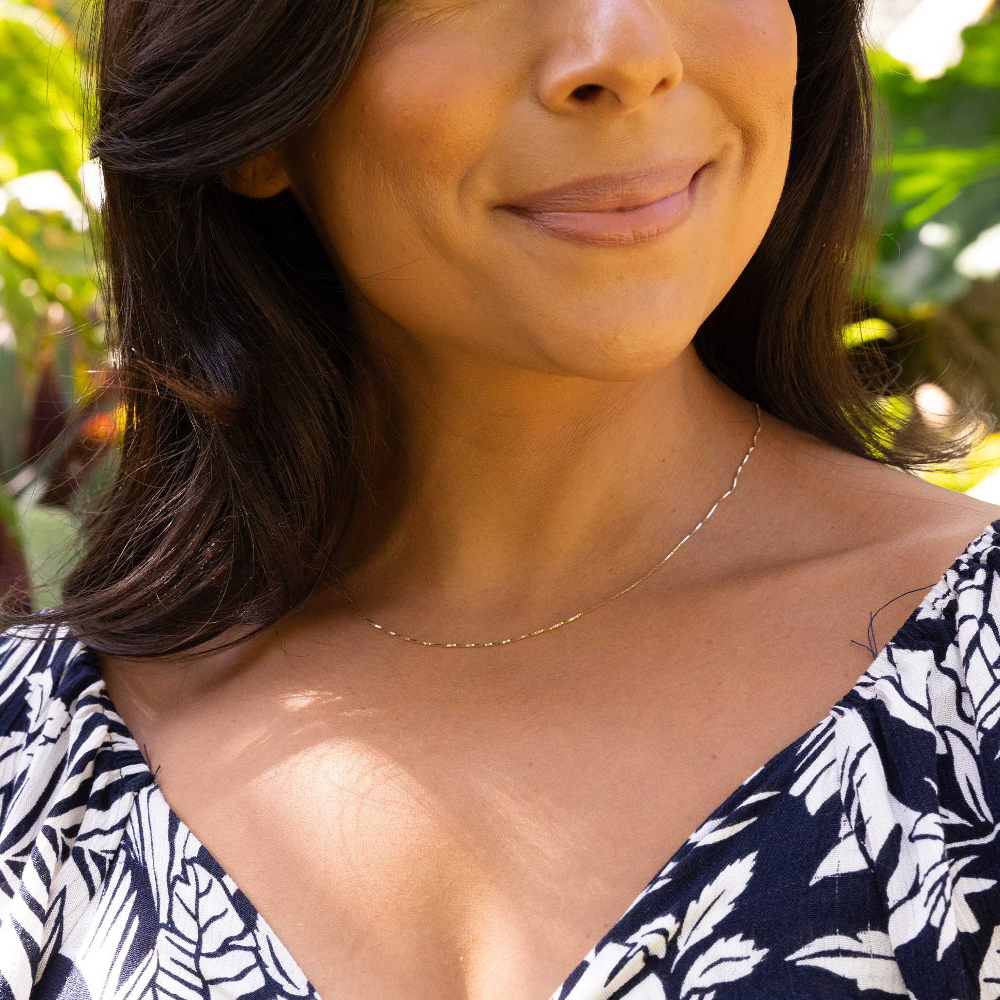 Close up of woman in a garden wearing 0.8mm Venetian Box Chain in Gold