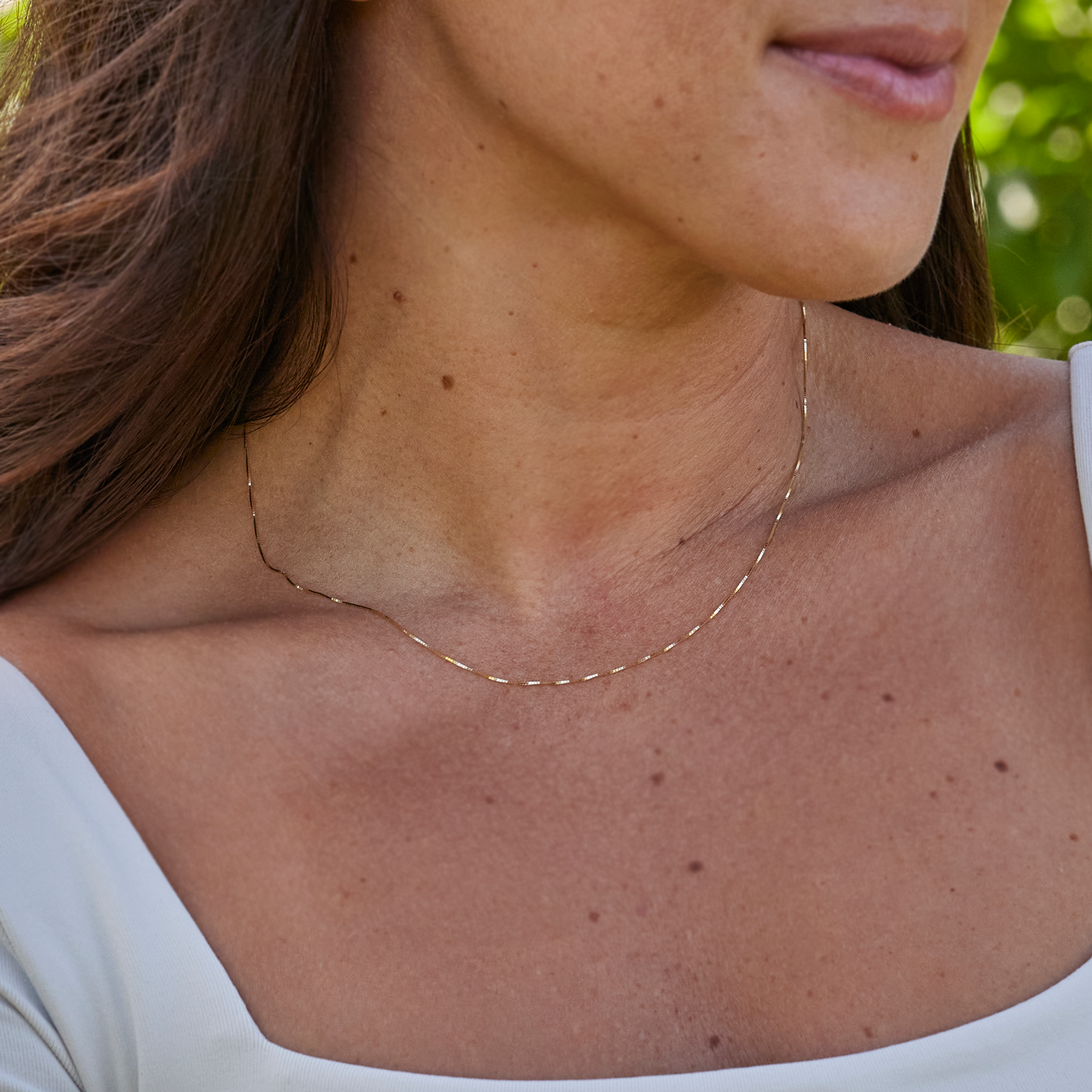 Close up of 0.6mm Lite Box Chain in Gold on a woman's neckline