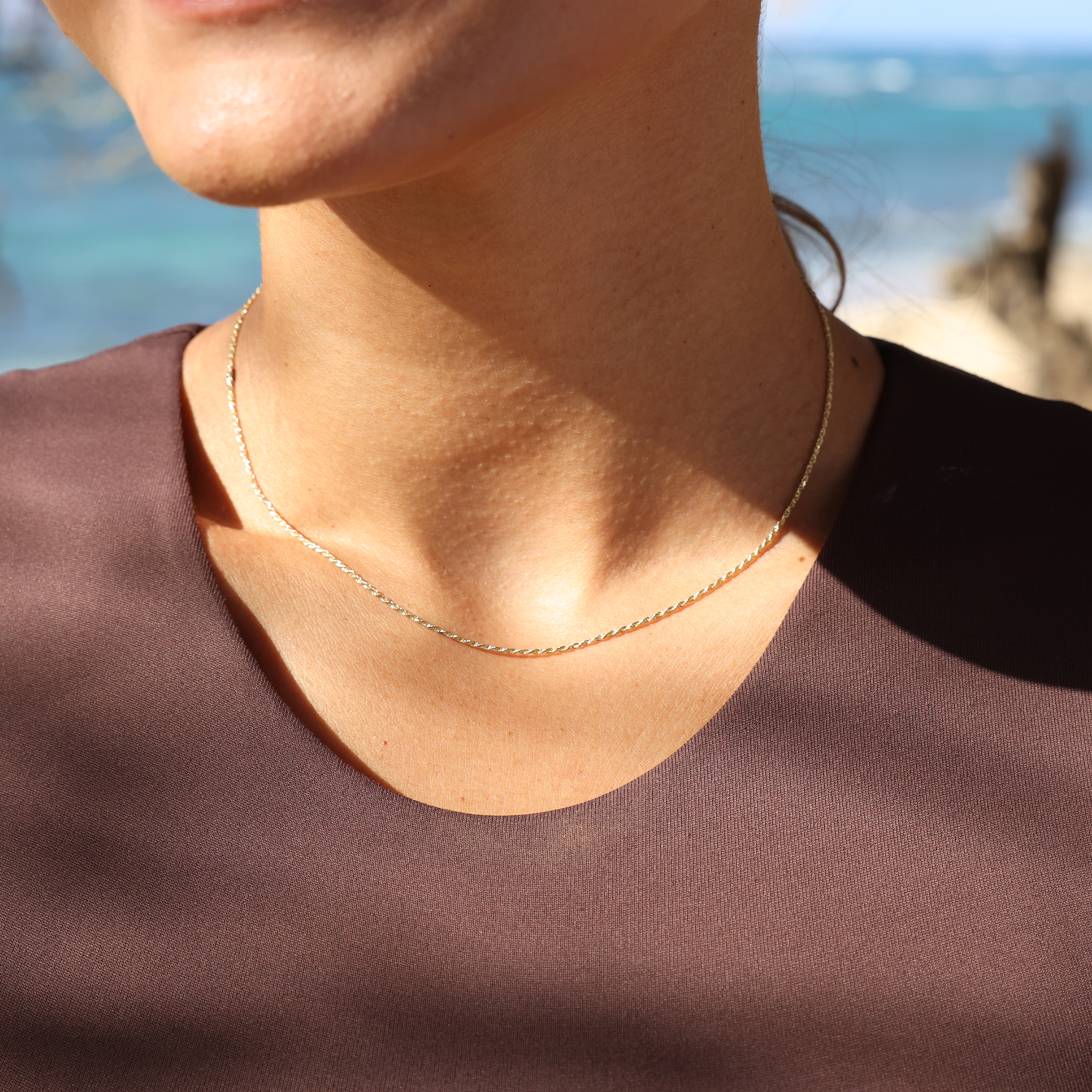 Close up of woman at the beach wearing 1.2mm Flex Rope Chain in Gold