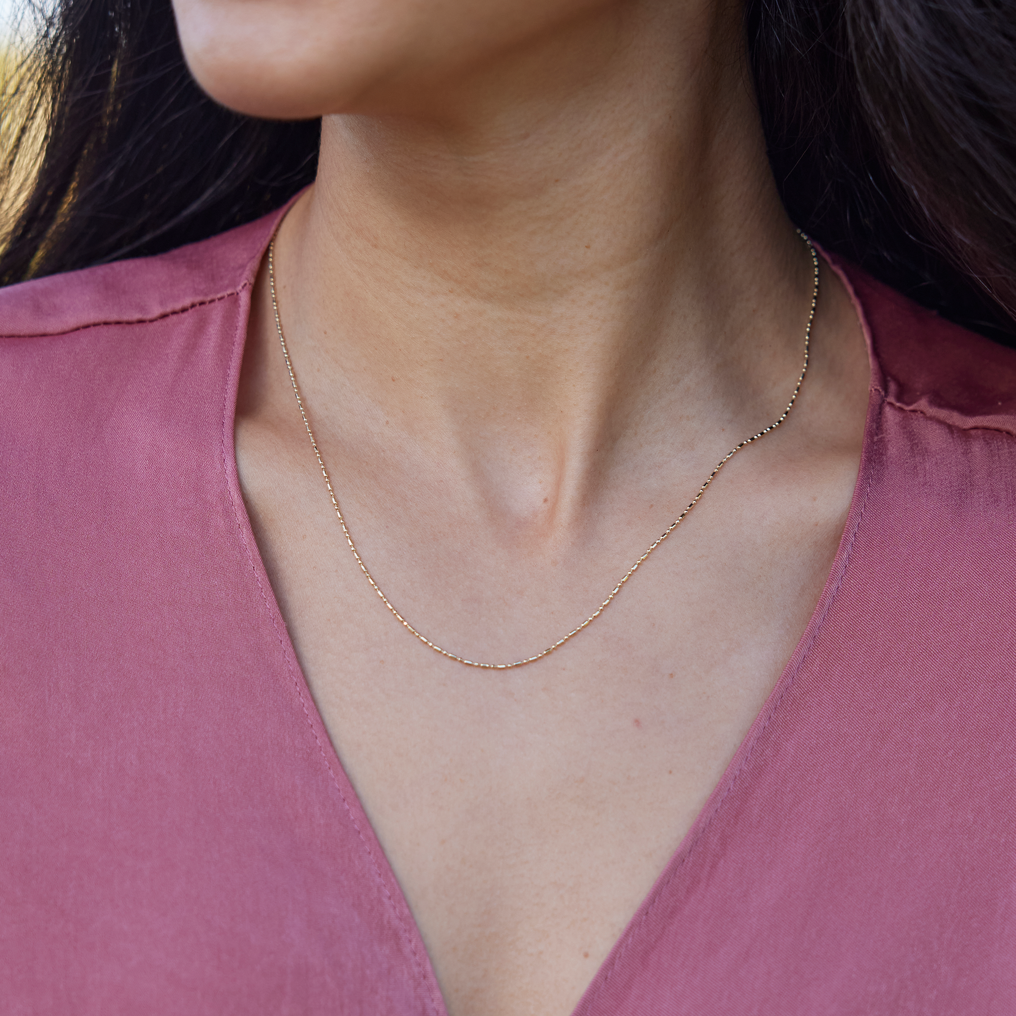 Close up of 1.0mm Bar Ball Chain in 14k Yellow Gold on woman's chest