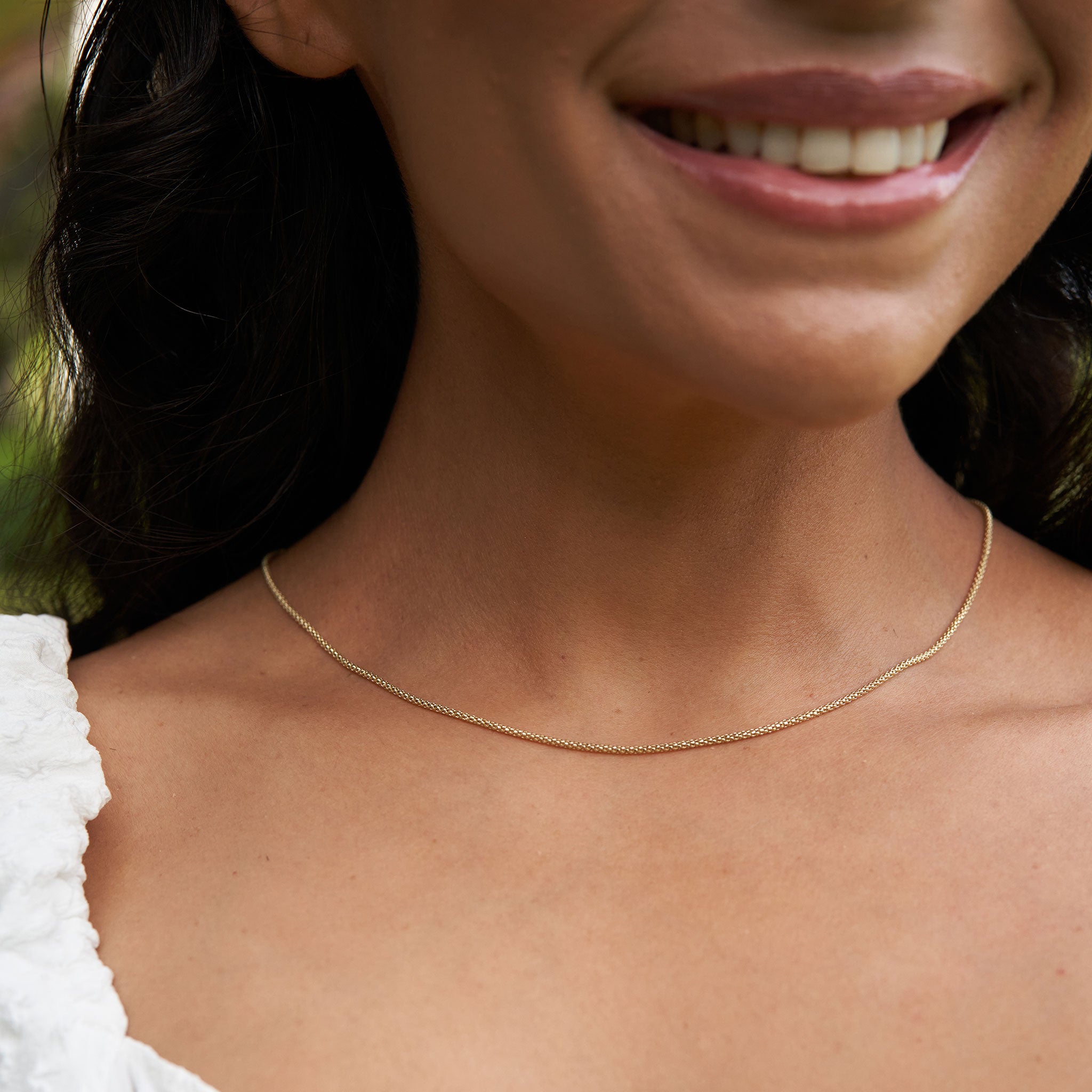Close up of 1.6mm Popcorn Chain in Gold on woman's neckline outdoors