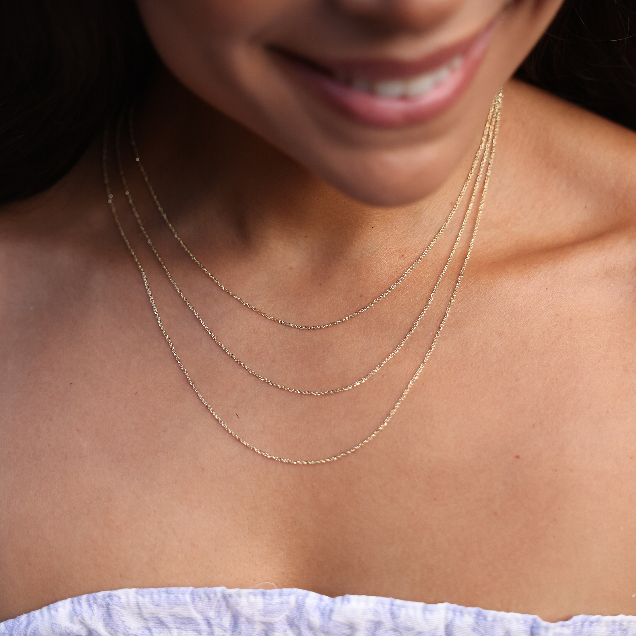 Close up of 3 different length chains on woman's chest