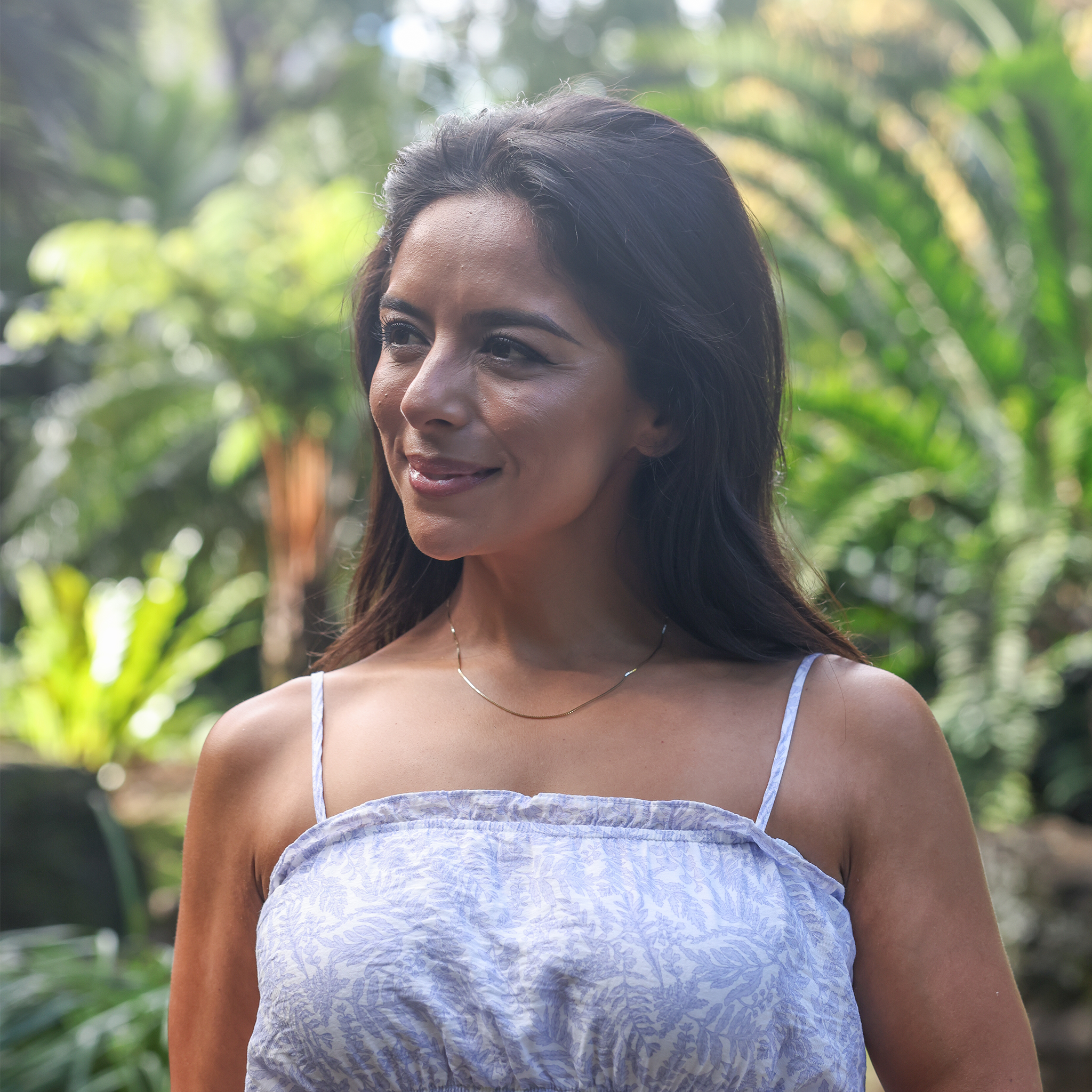 Woman in a tropical garden wearing 1.0mm Box Chain in Gold