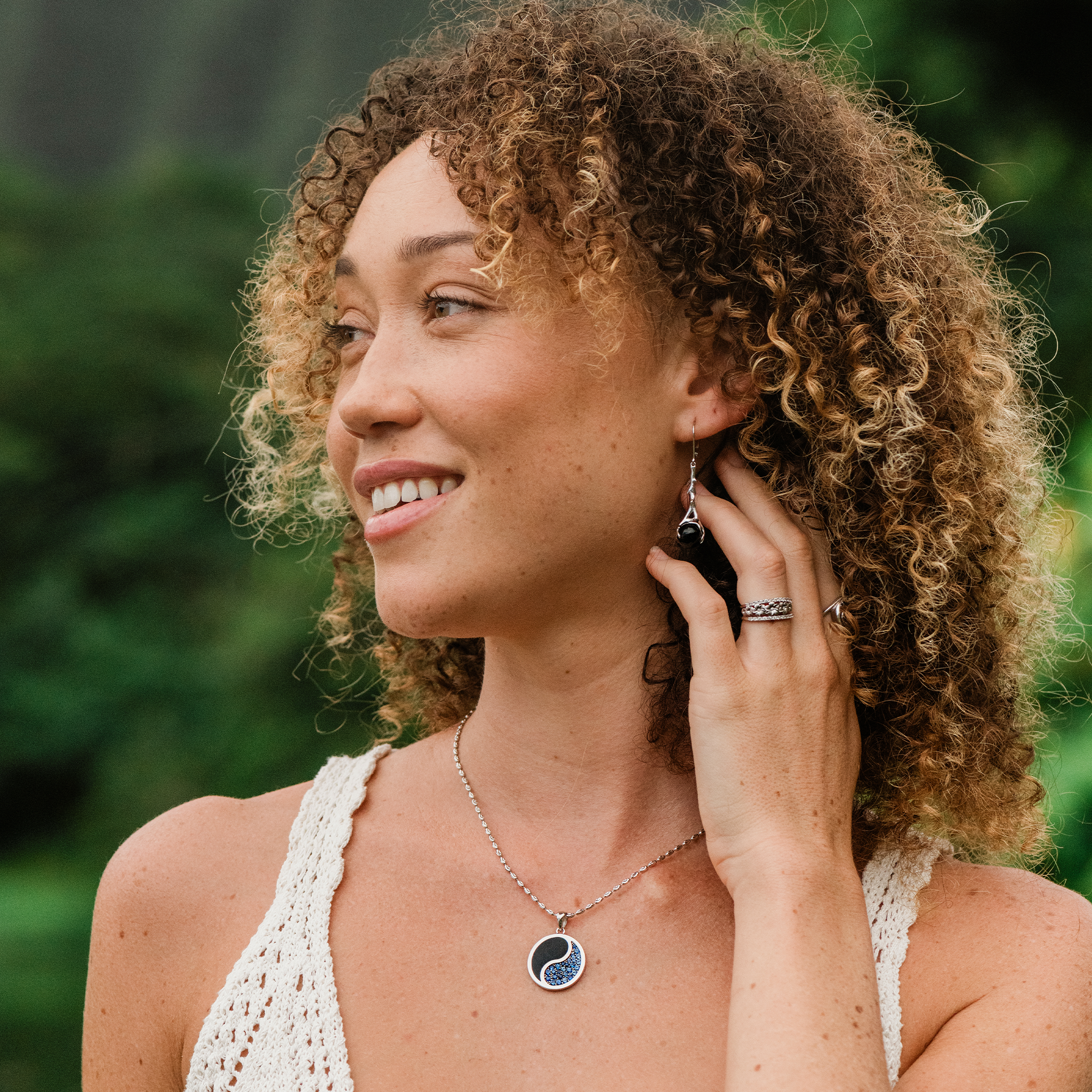 Woman in a garden wearing 1.8mm Ovalina Chain in White Gold with a yin yang pendant