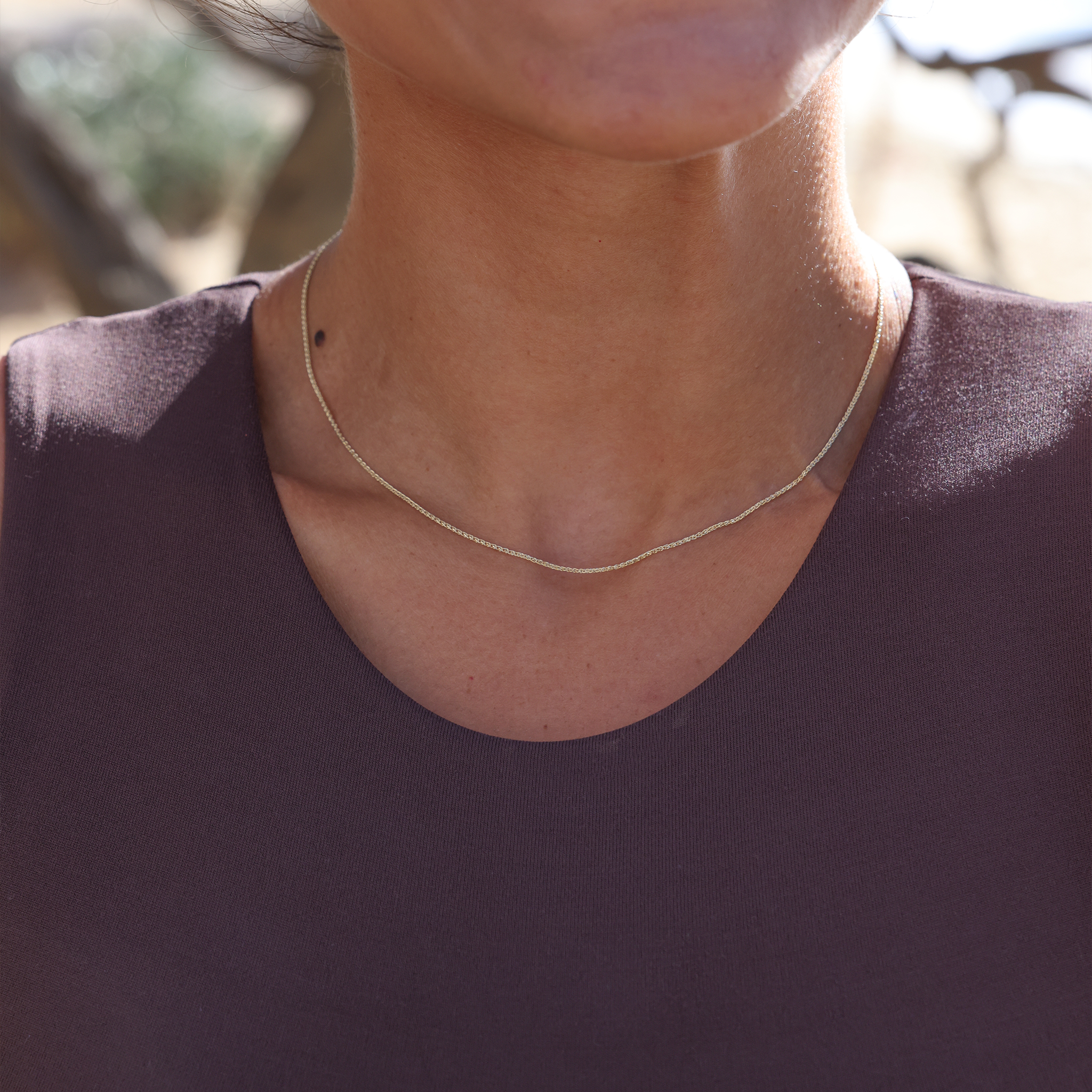 Close up of 1.2mm Espiga Chain in Gold on a neckline outdoors