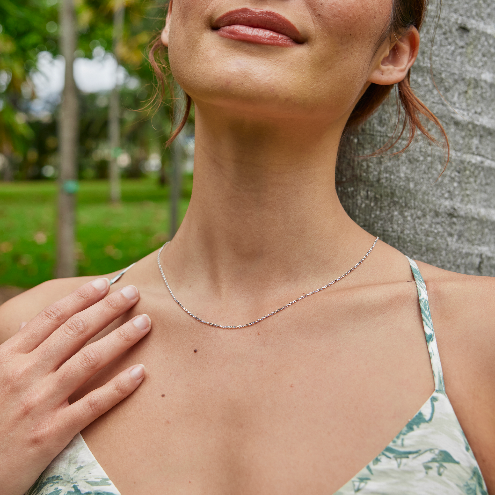 Close up of a woman at a park wearing 1.0mm Cable Chain in 14k White Gold