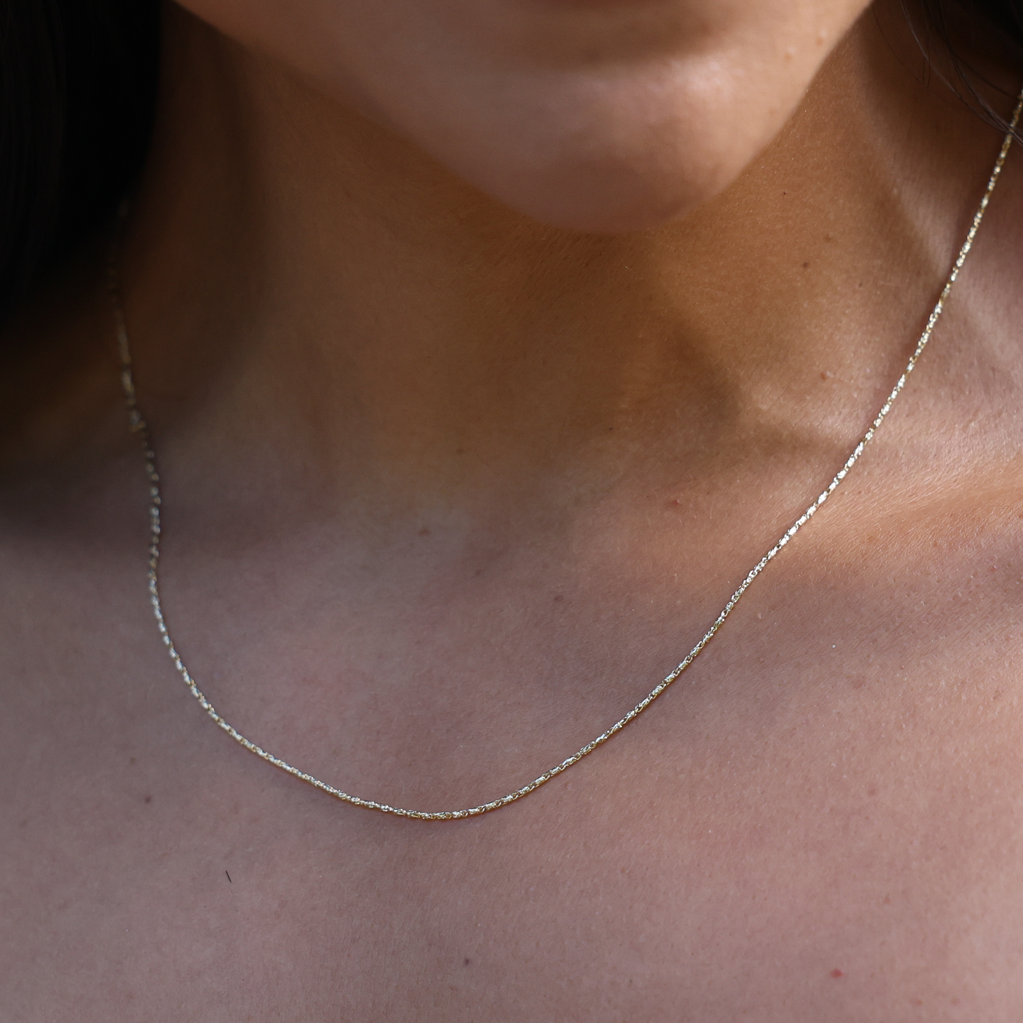 Close up of 0.9mm Raso Chain in 14k Yellow Gold on a neckline