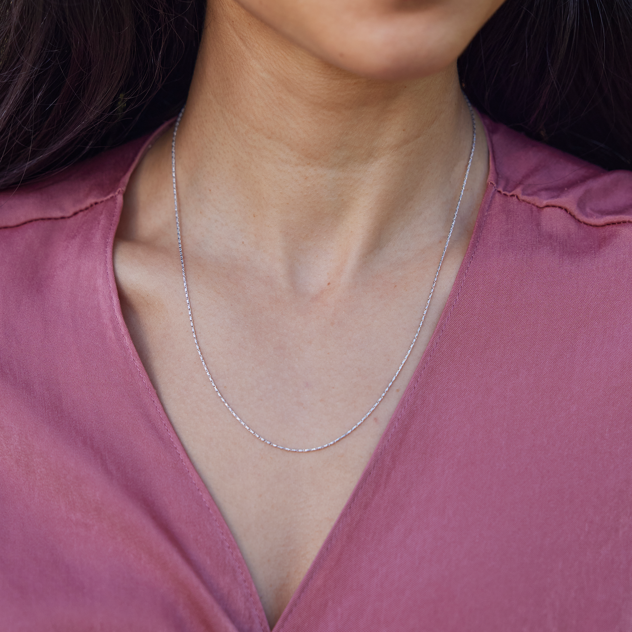 Close up of 0.9mm Raso Chain in 14k White Gold on a woman's chest with pink top