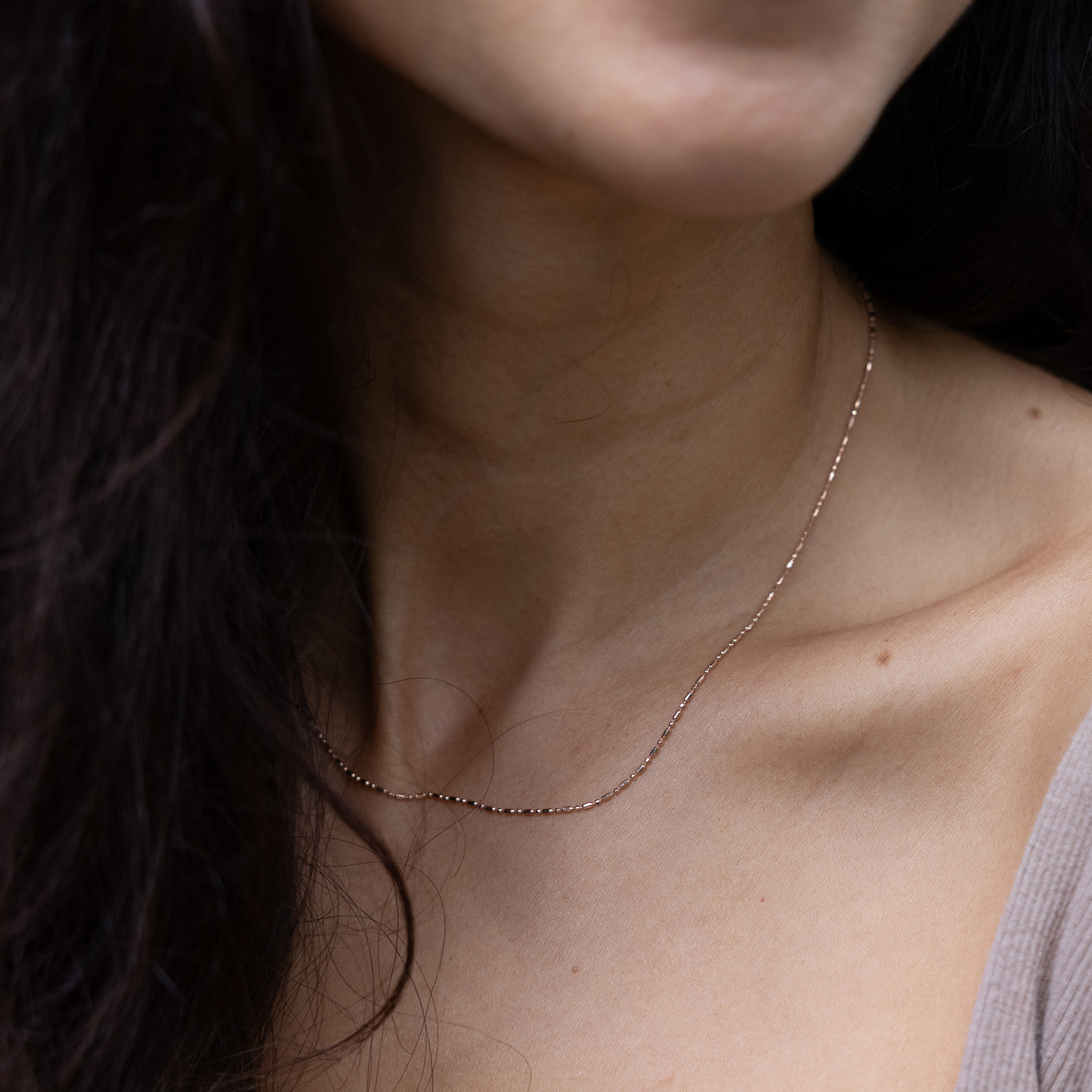 Close up of 1.0mm Ball Bar Chain in 14k Rose Gold on a womanʻs chest