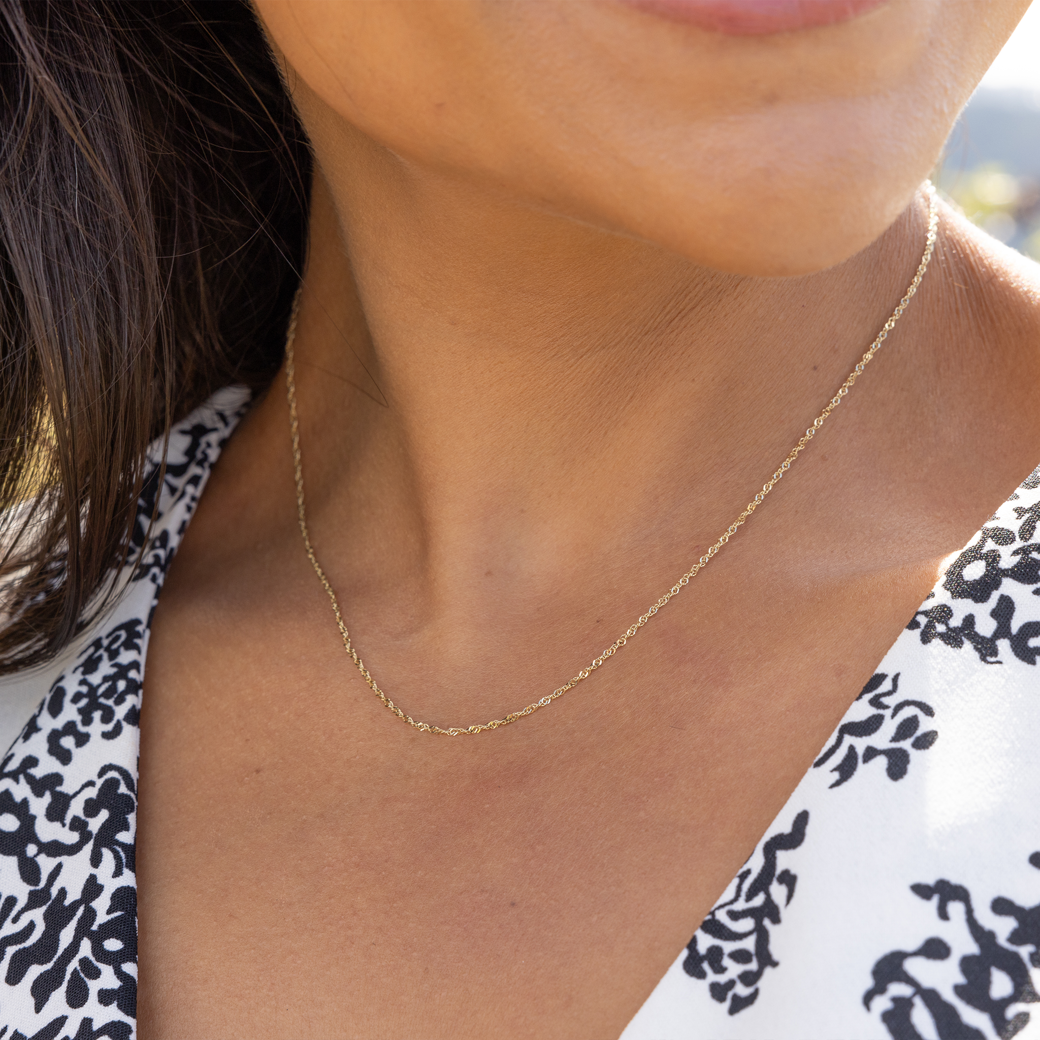 Close up of 1.0mm Singapore Chain in Gold on a womanʻs neckline