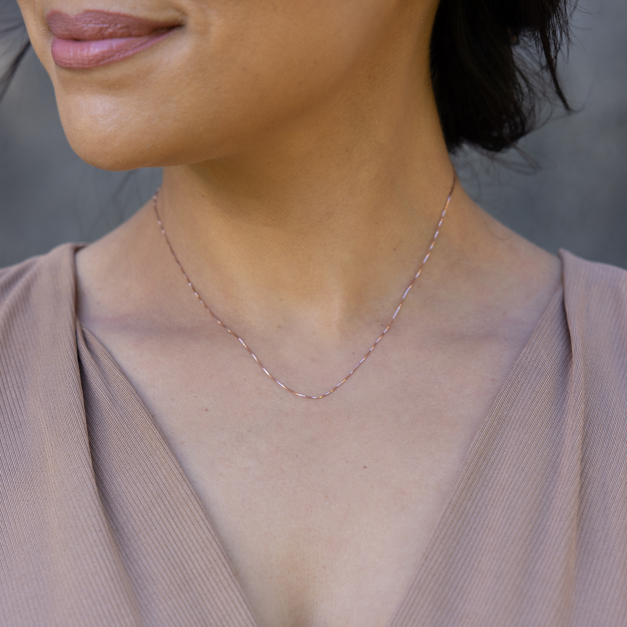 Close up of 0.6mm Lite Box Chain in 14k Rose Gold on a womanʻs neckline