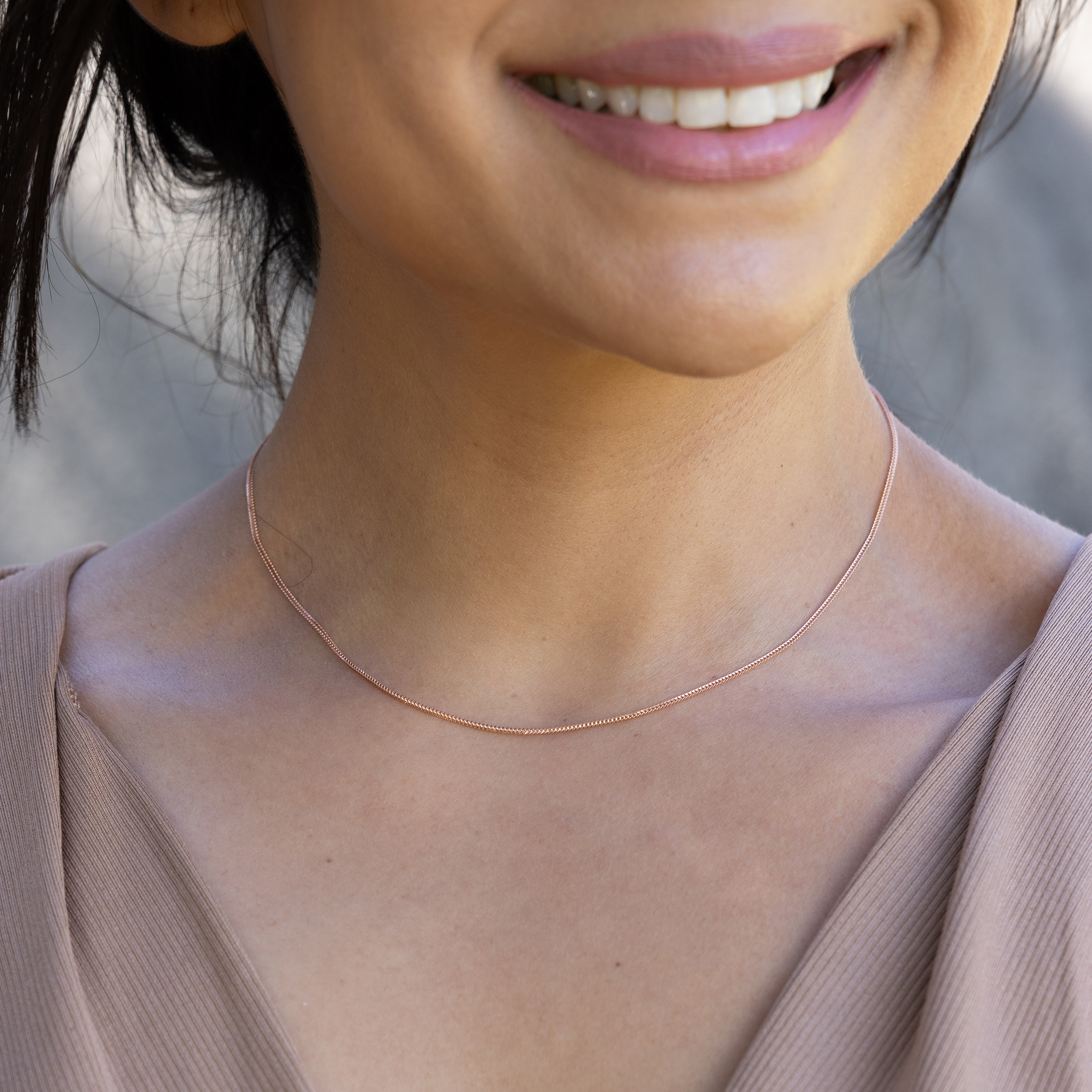 Close up of 1.2mm Singapore Foxtail Chain in 14k Rose Gold on a womanʻs neckline