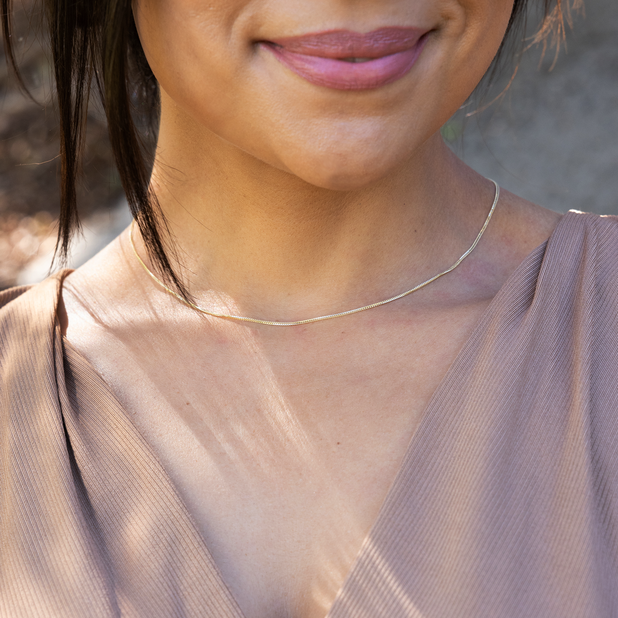 Close up of 1.2mm Singapore Foxtail Chain in 14k yellow Gold on a womanʻs chest