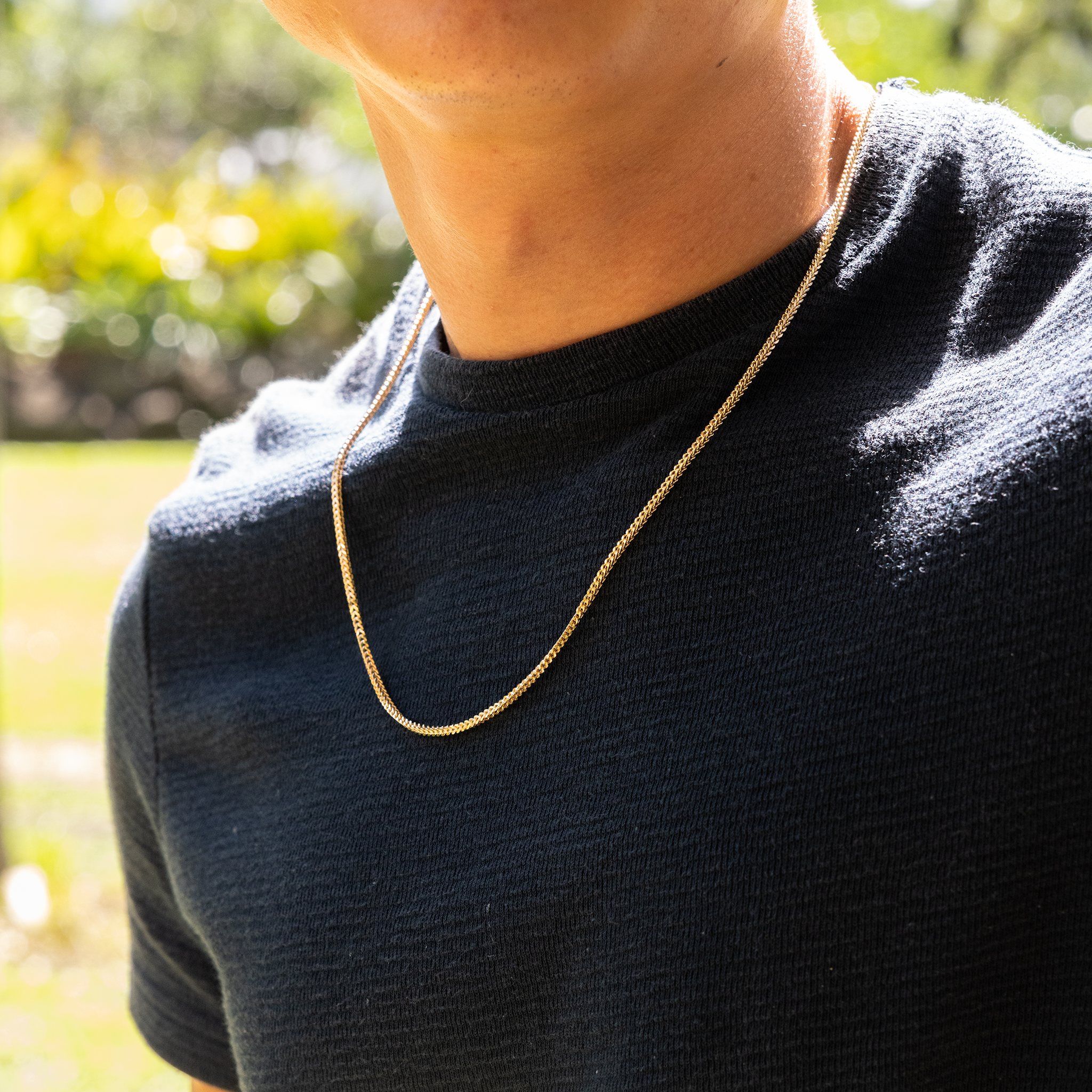 Close up of man wearing 2.5mm Hollow Franco Chain in 14k Yellow Gold outdoors
