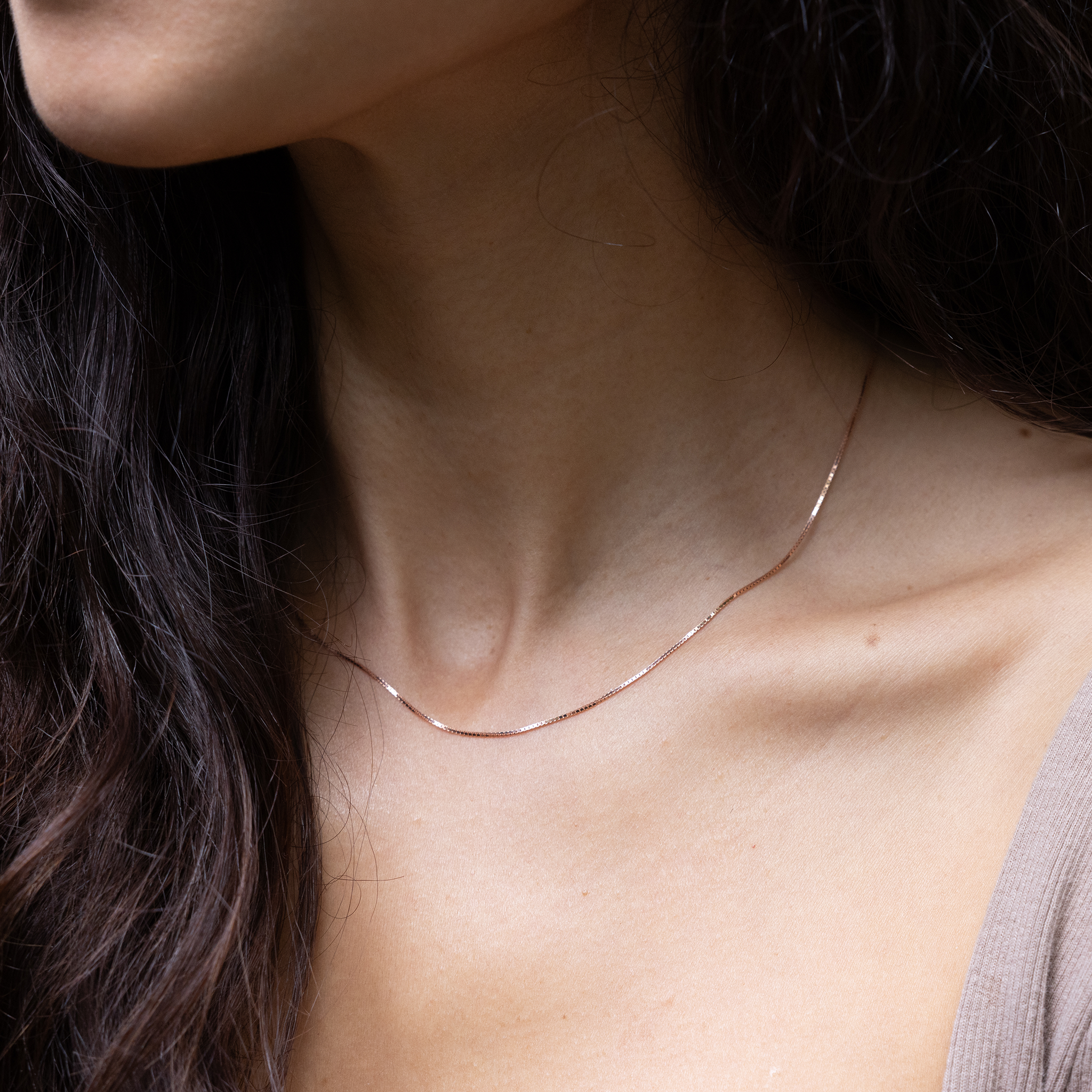 Close up of 0.7mm Box Chain in 14k Rose Gold on a womanʻs neckline