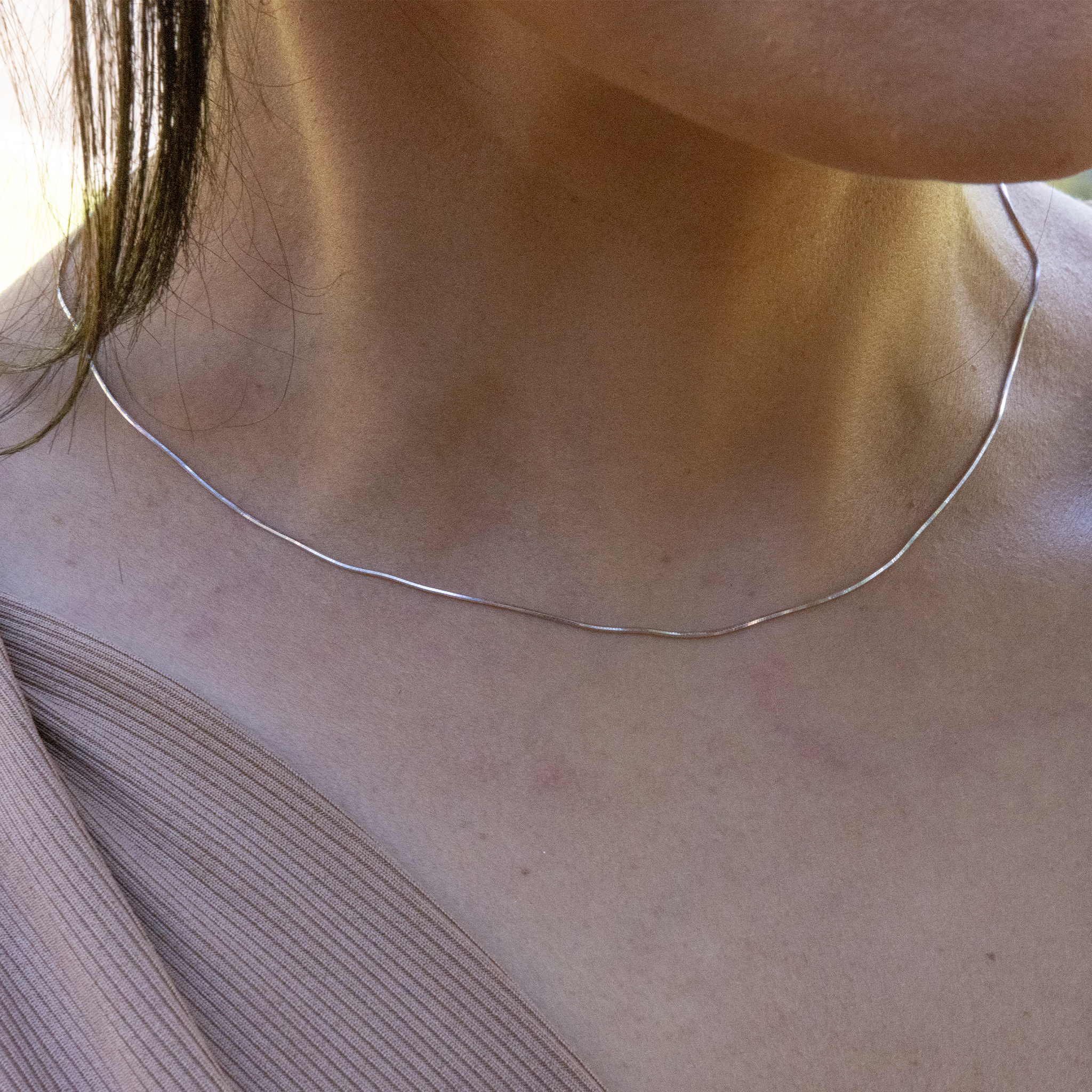 Close up of 1.0mm Snake Chain in Sterling Silver on a womanʻs neckline