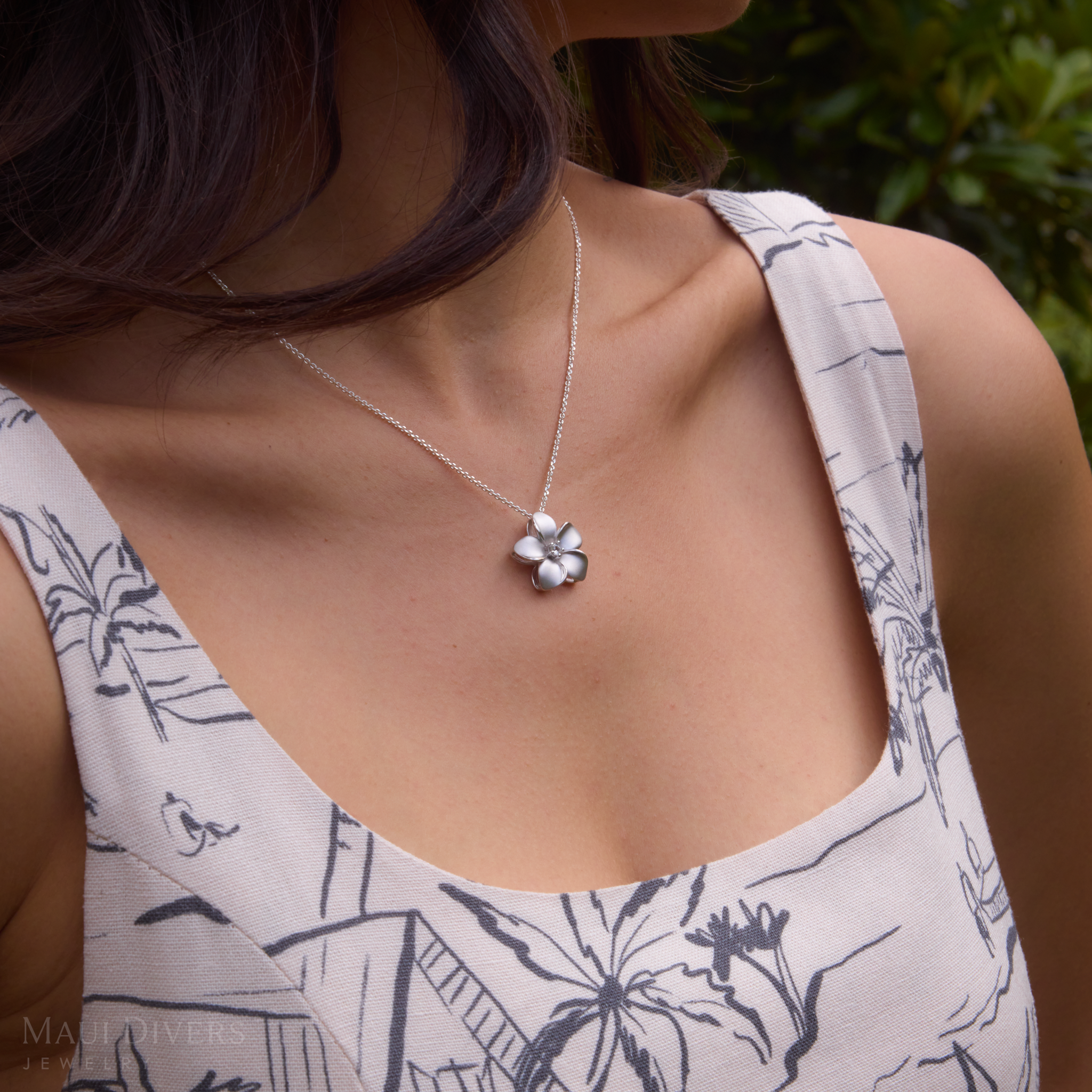 Close up of woman's chest wearing Plumeria White Sapphire Necklace in Sterling Silver