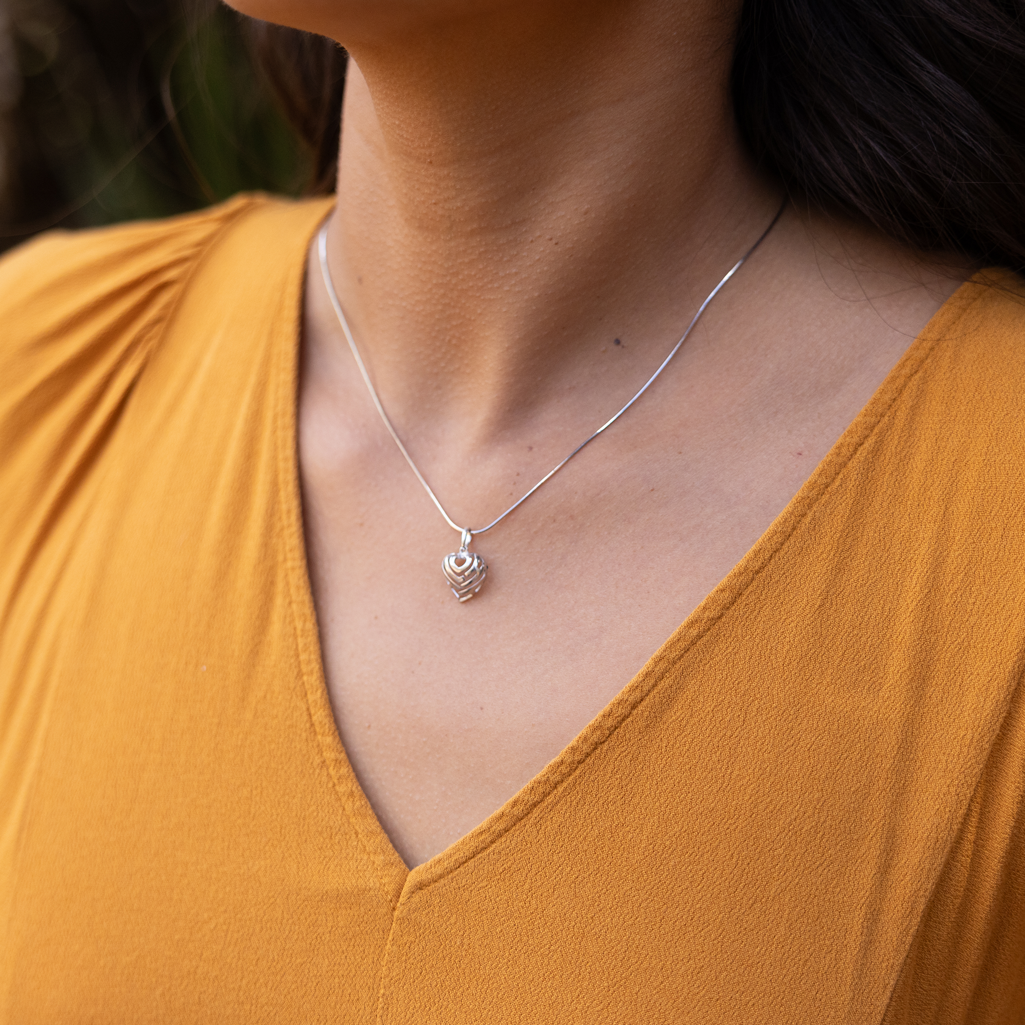 Close up of an Aloha Heart Charm/Pendant in Sterling Silver on a person's chest