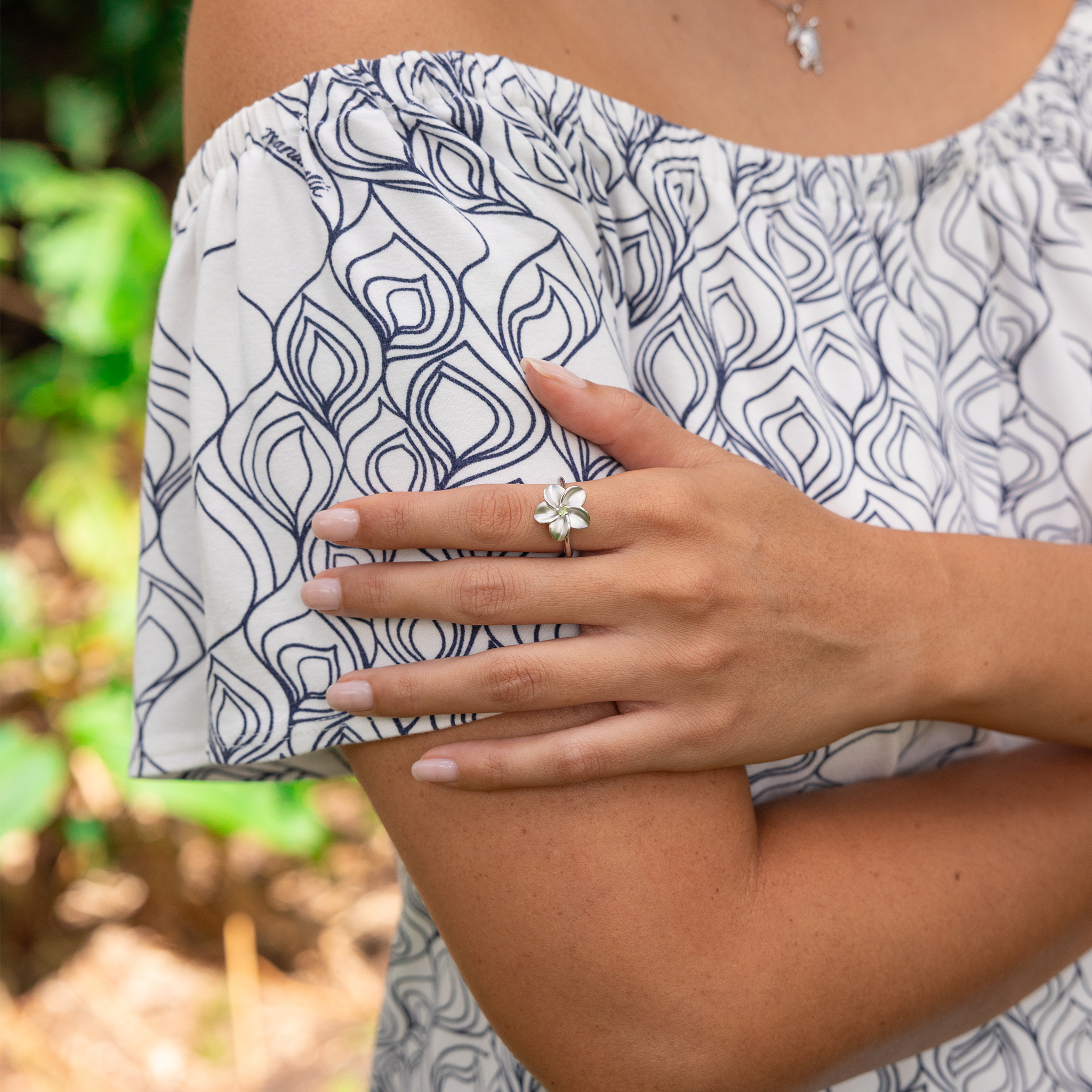 Close up of a womans hand wearing a Plumeria Peridot Ring in Sterling Silver