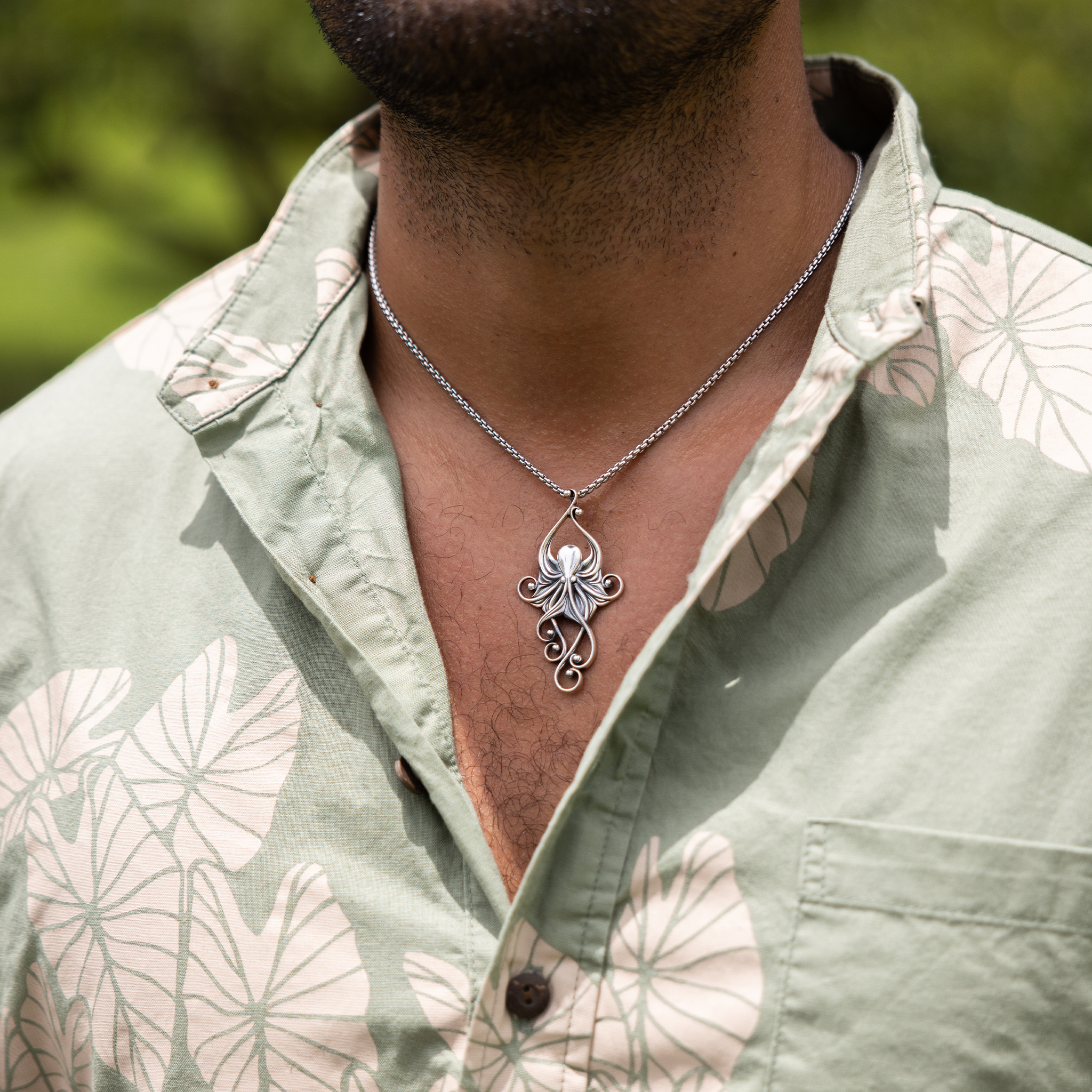 Close up of Living Heirloom Octopus Pendant in Sterling Silver on a man's chest outdoors