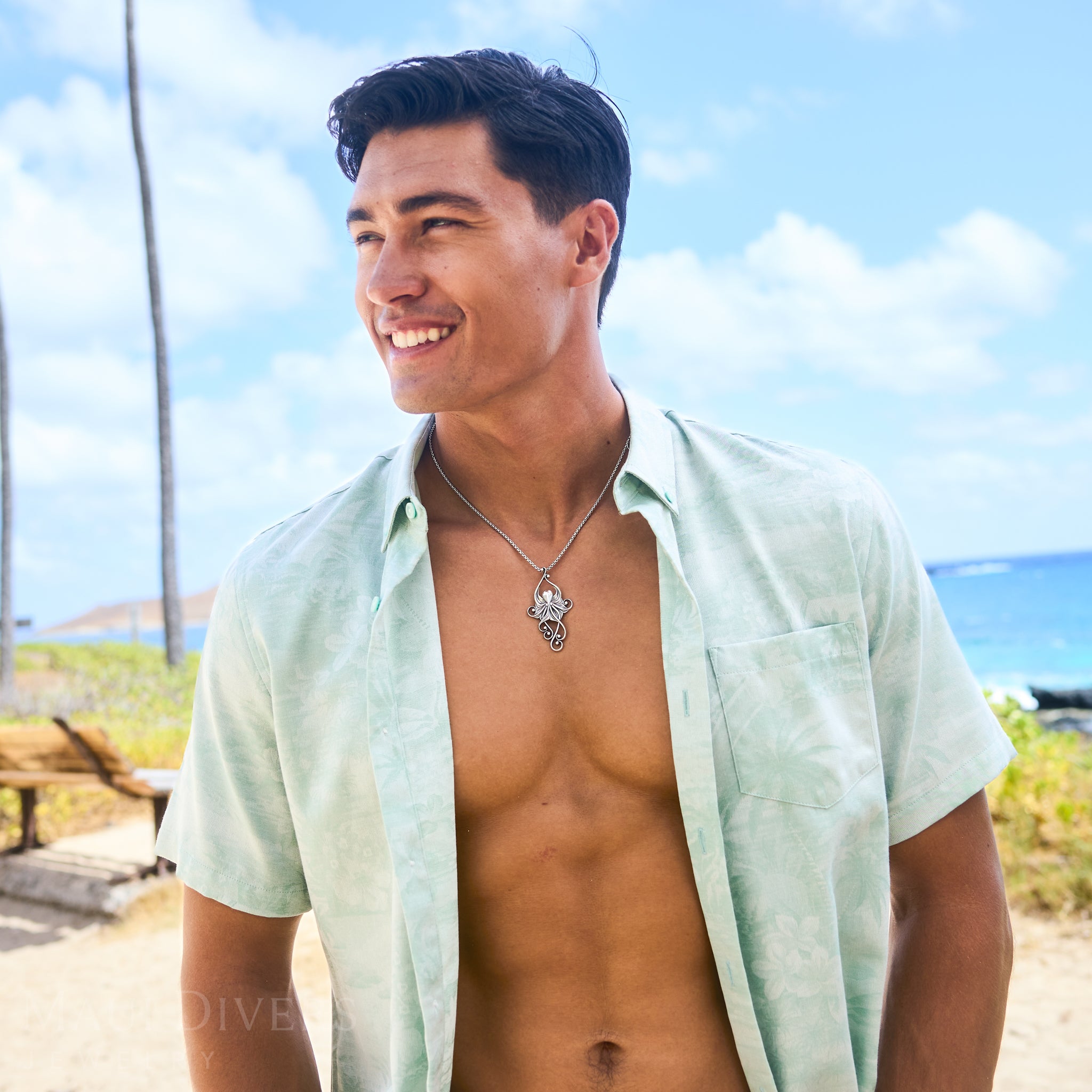 Man with a light green shirt standing on a beach wearing a Living Heirloom Octopus Pendant in Sterling Silver