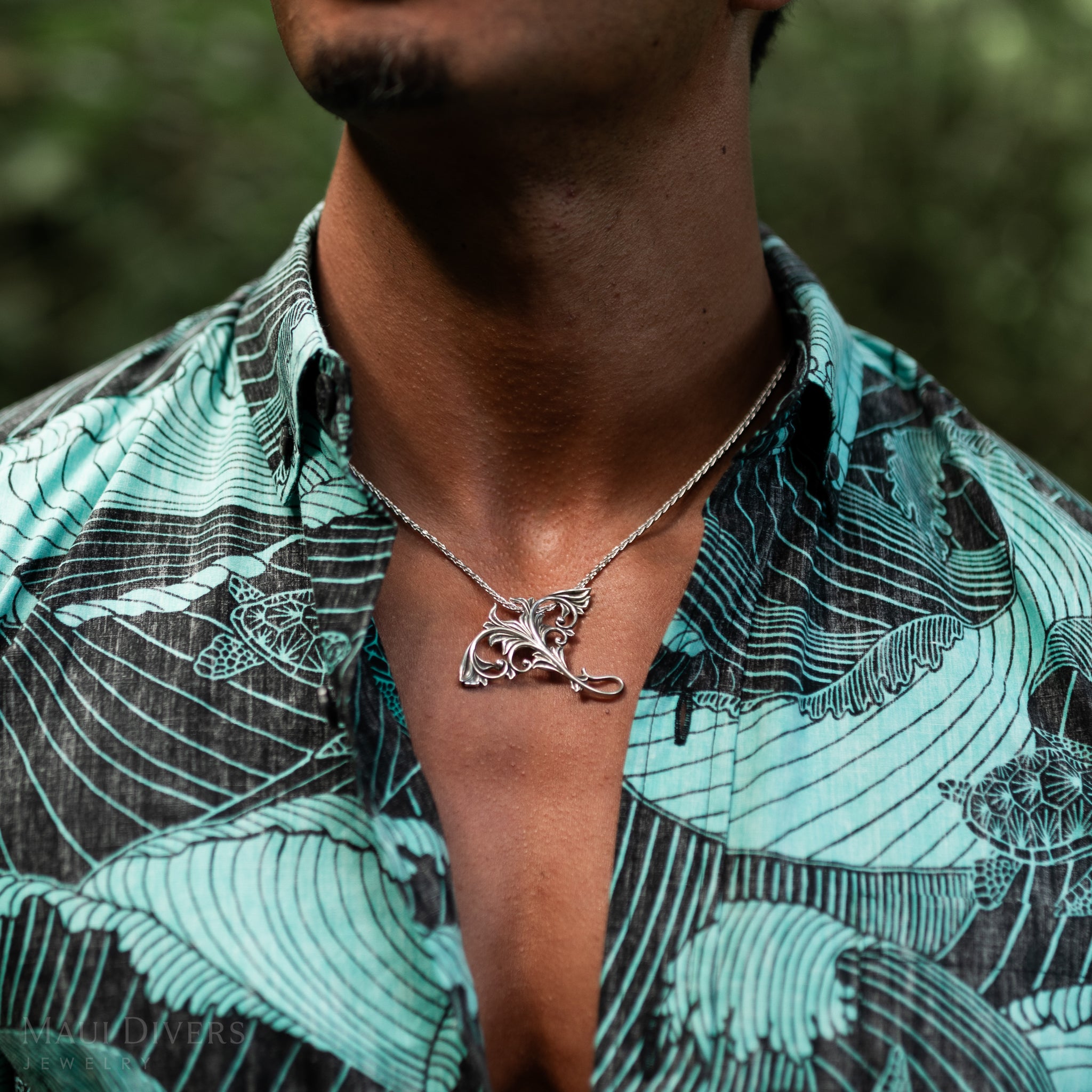 Close up of Living Heirloom Manta Ray Pendant in Sterling Silver on a man's chest outdoors