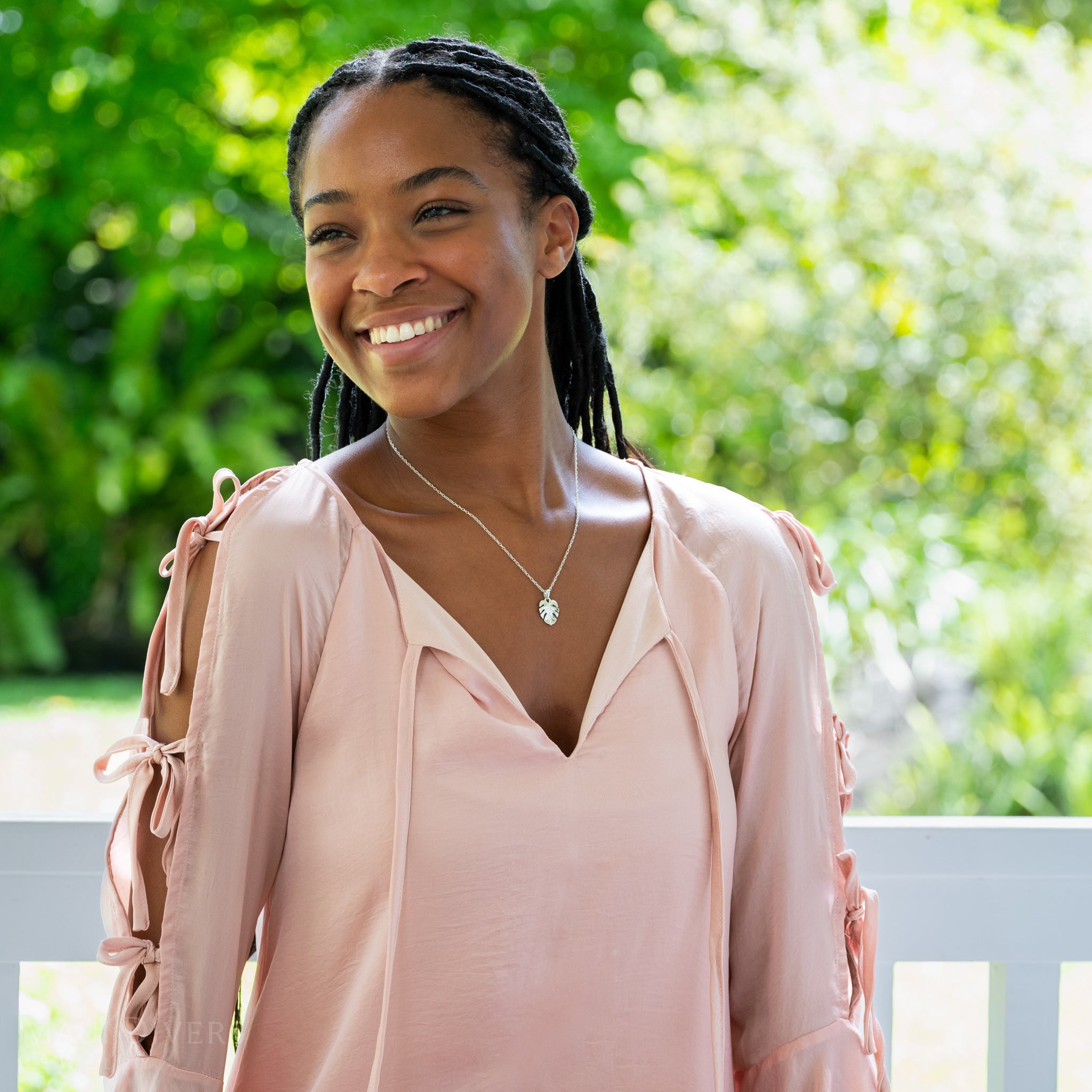 Woman in a pink blouse with greenery in the background wearing a Monstera Pendant in Sterling Silver