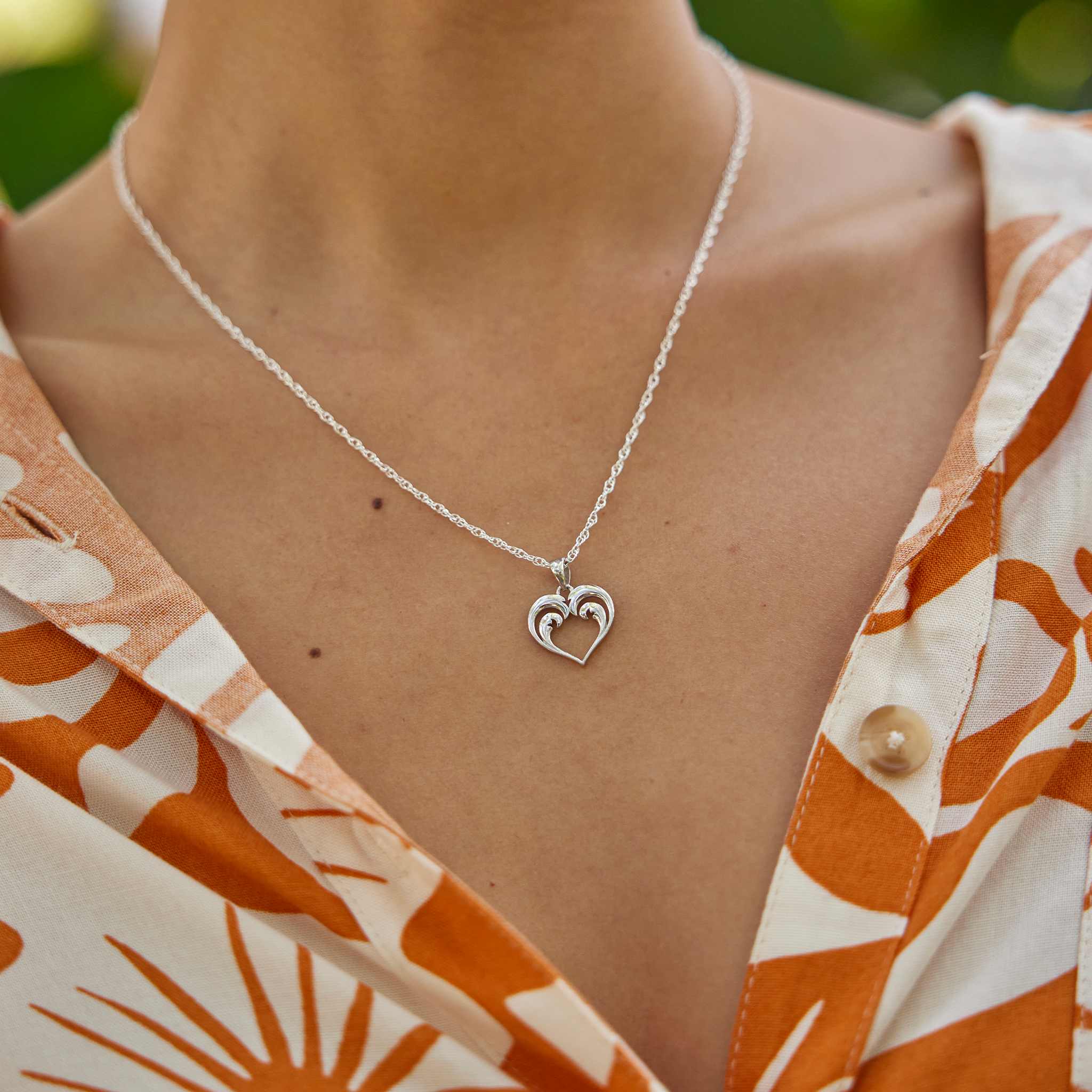 Close up of Nalu Heart Pendant Necklace in Sterling Silver on a woman's chest outdoors