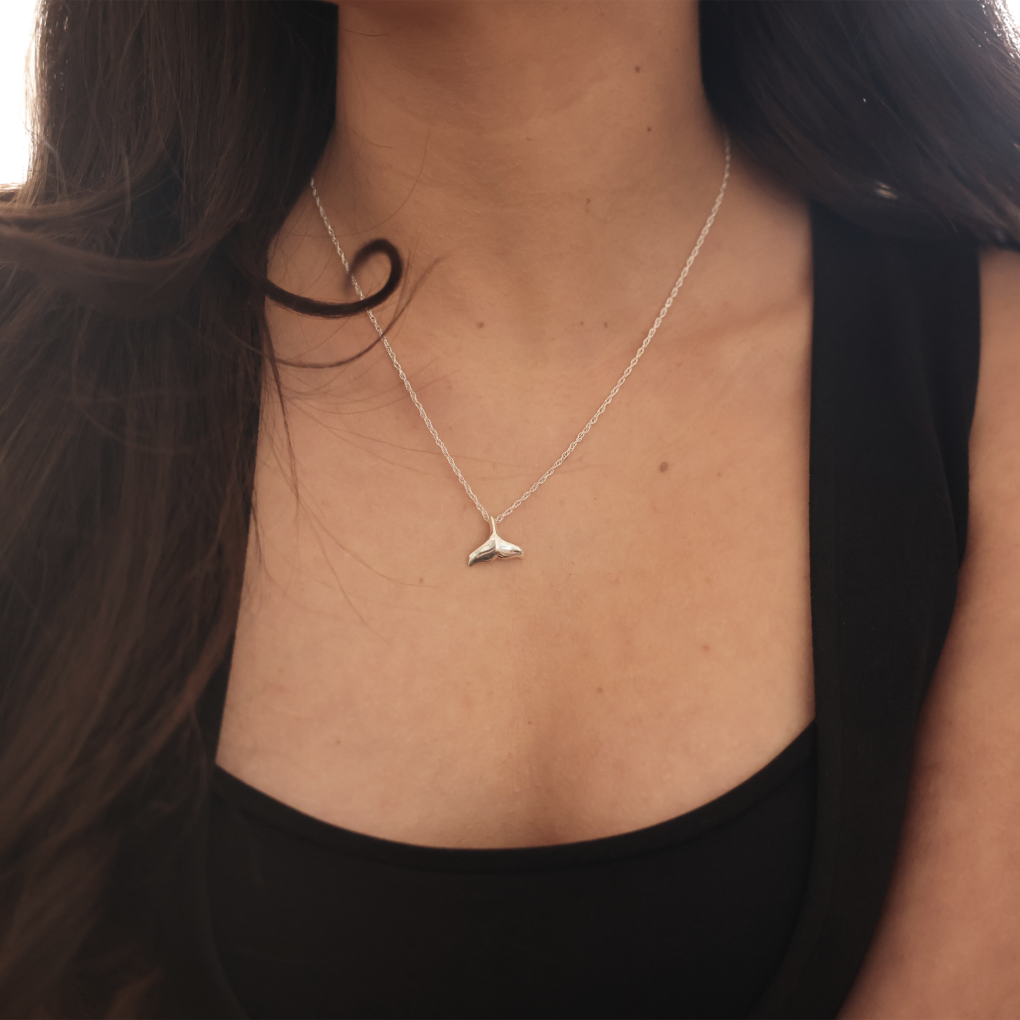 Close up of a Whale Tail Pendant Necklace in Sterling Silver on a woman's chest