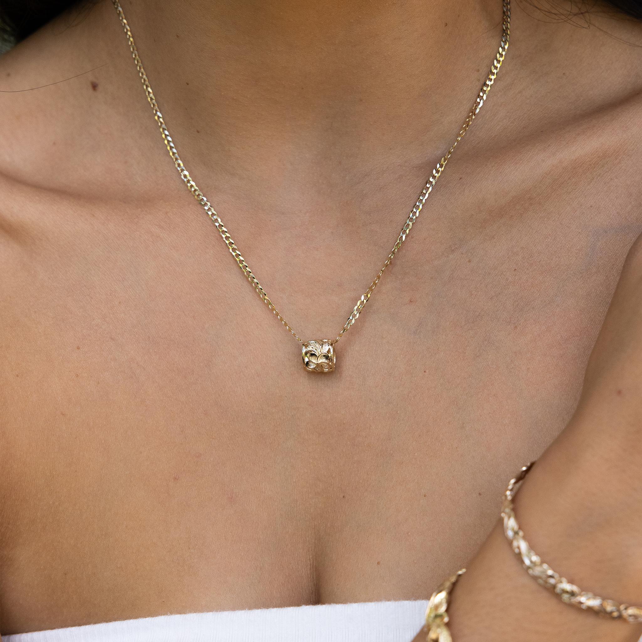 Close up of Hawaiian Heirloom Plumeria Barrel Pendant in Gold on a woman's chest