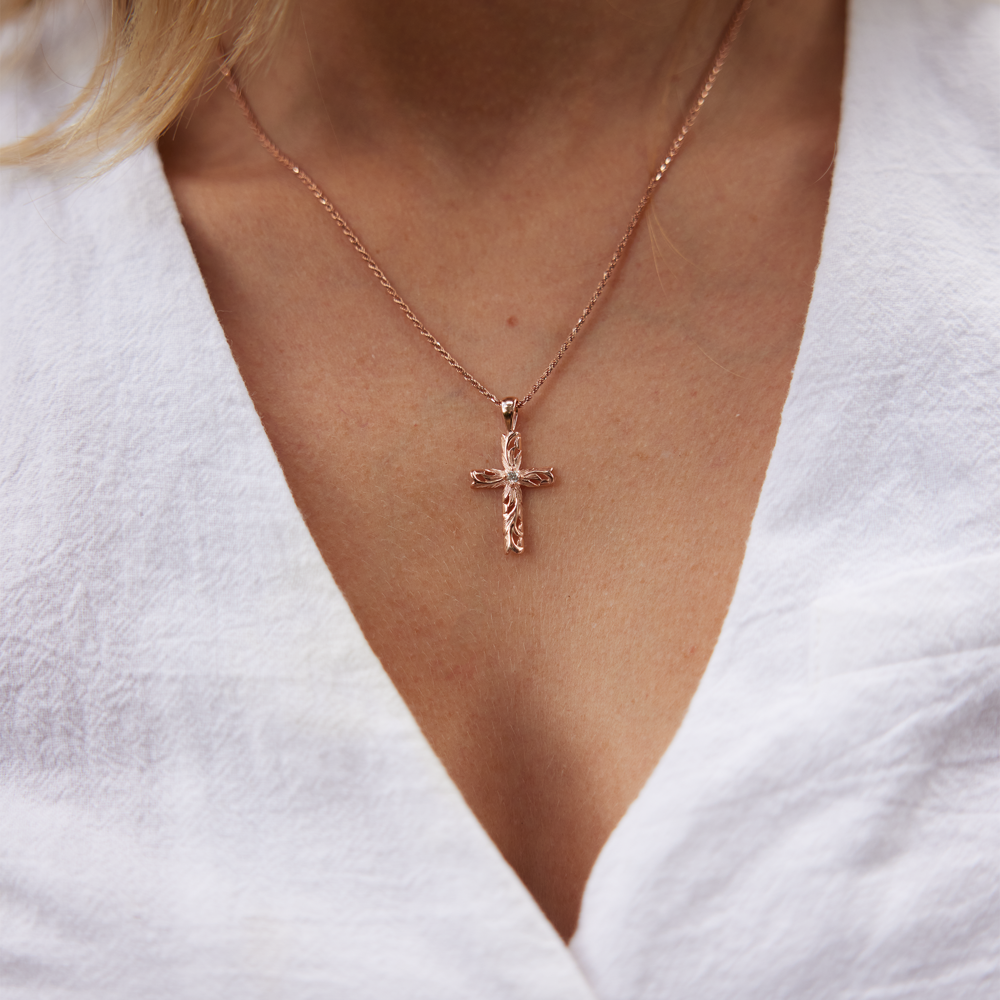Womanʻs neckline showcasing Hawaiian Heirloom Old English Scroll Cross Pendant in Rose Gold with Diamond - 30mm