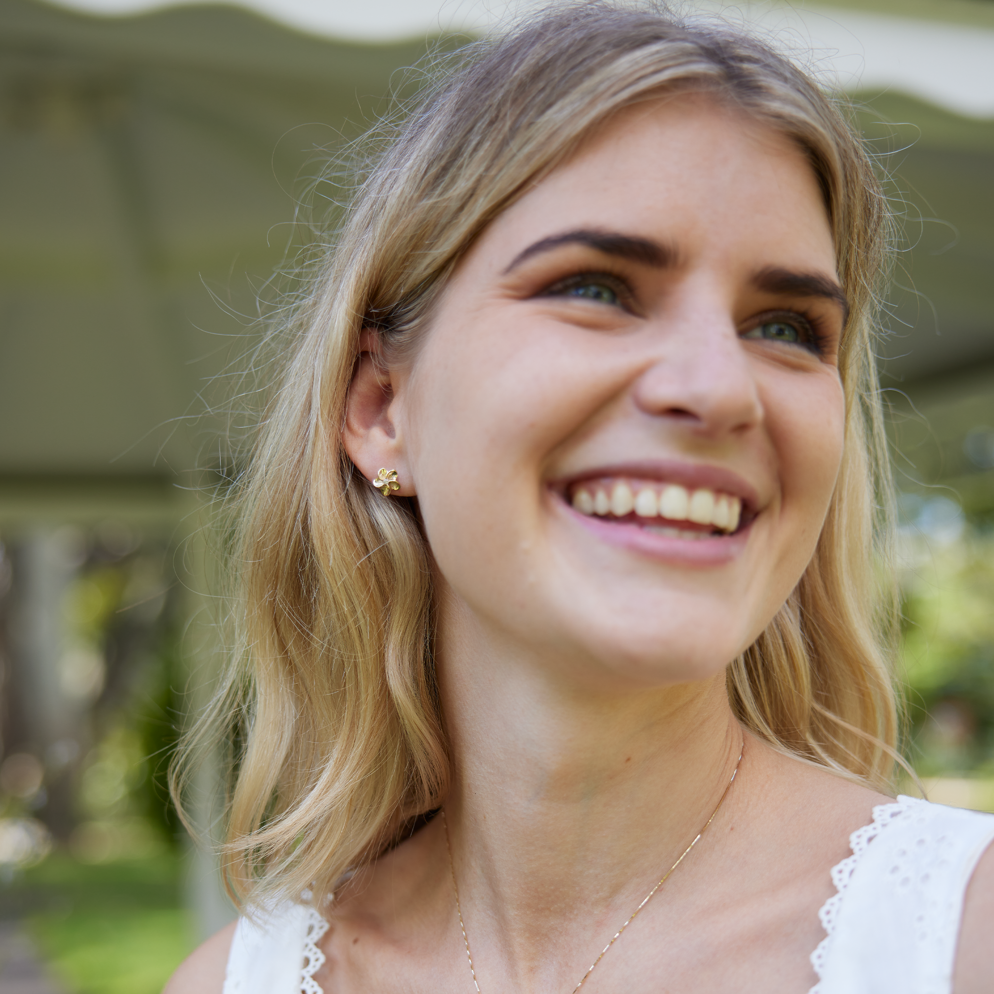 Blurred woman wearing Hawaiian Heirloom Plumeria Earrings in Gold with Diamonds
