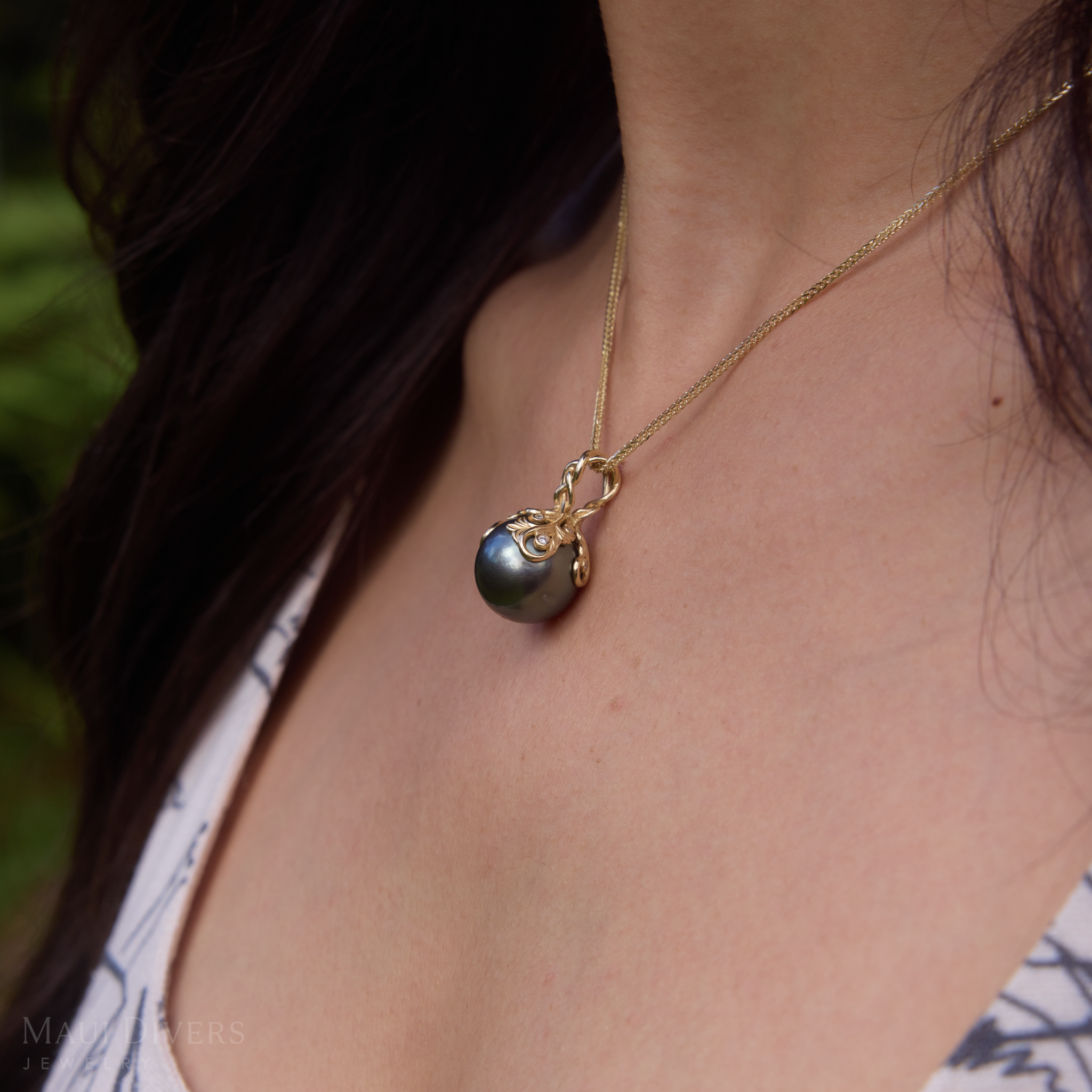Close up of Living Heirloom Tahitian Black Pearl Pendant in Gold with Diamonds on a woman's chest