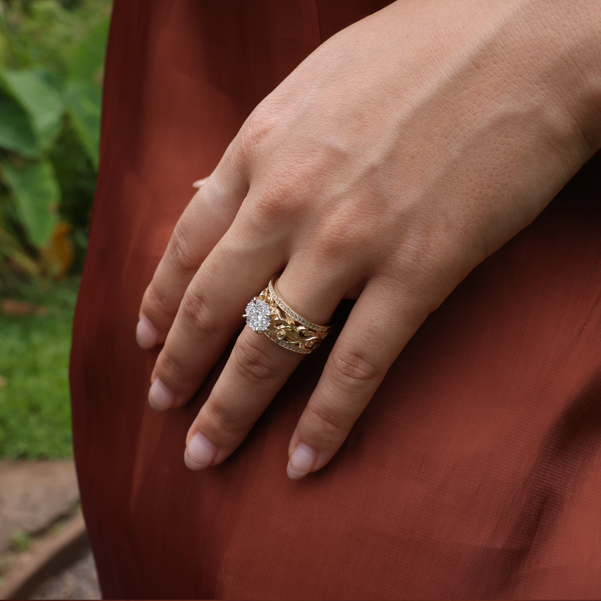 A woman's hand wearing a Living Heirloom Engagement Ring in Gold with Diamonds against a brown dress