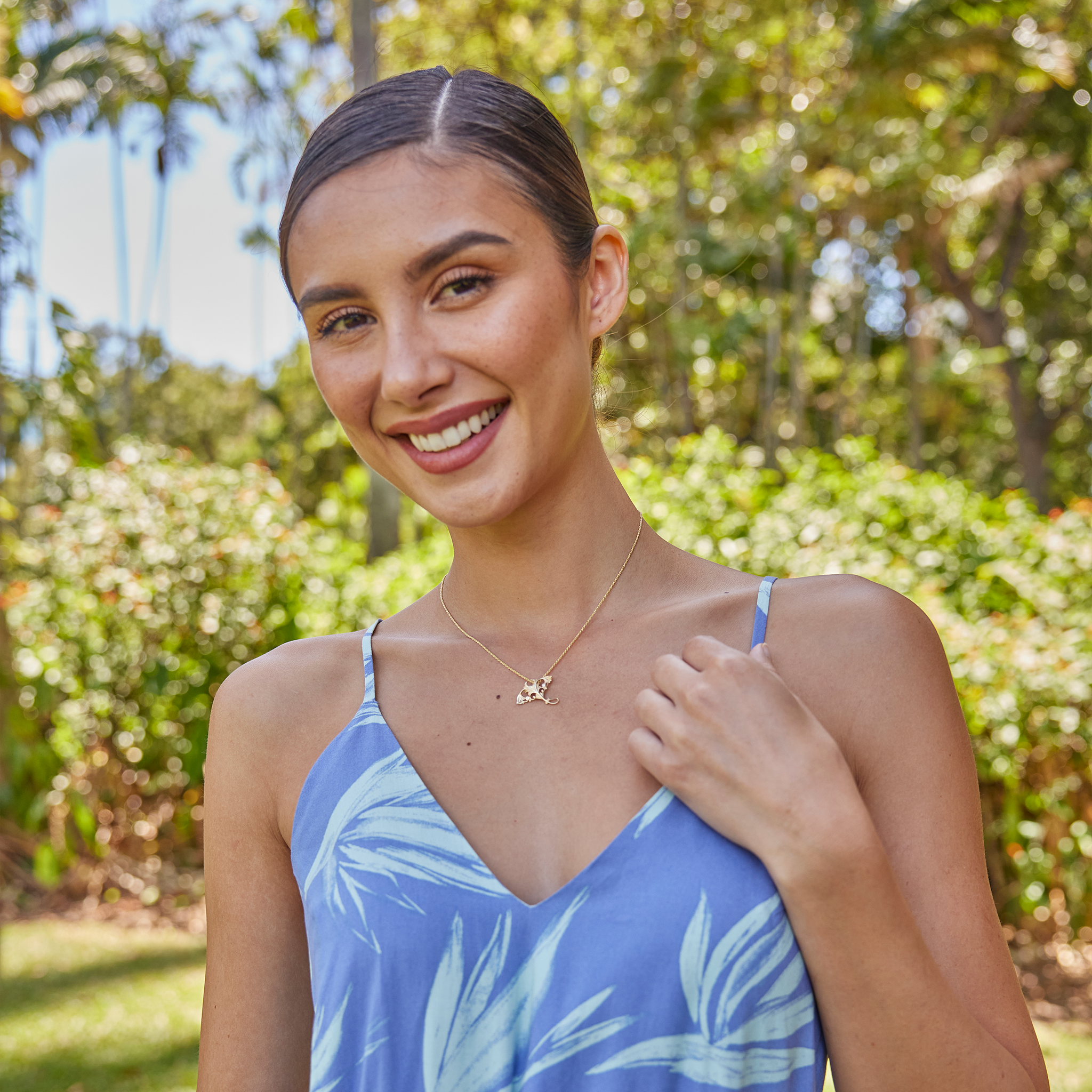 Woman in a garden wearing a Living Heirloom Manta Ray Pendant in Gold with Diamonds