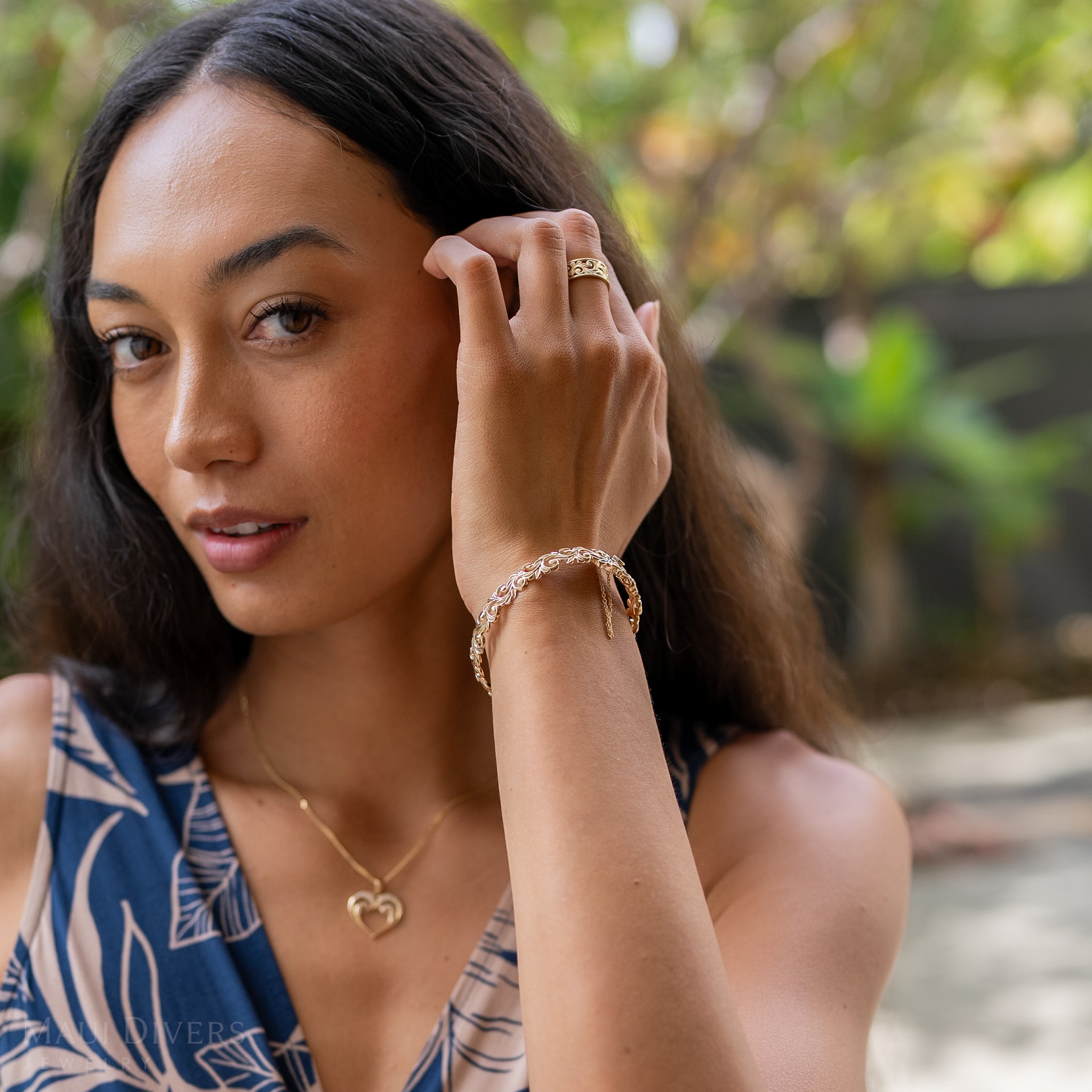 Woman in a garden wearing a Living Heirloom Hinge Bracelet in 14k Yellow Gold