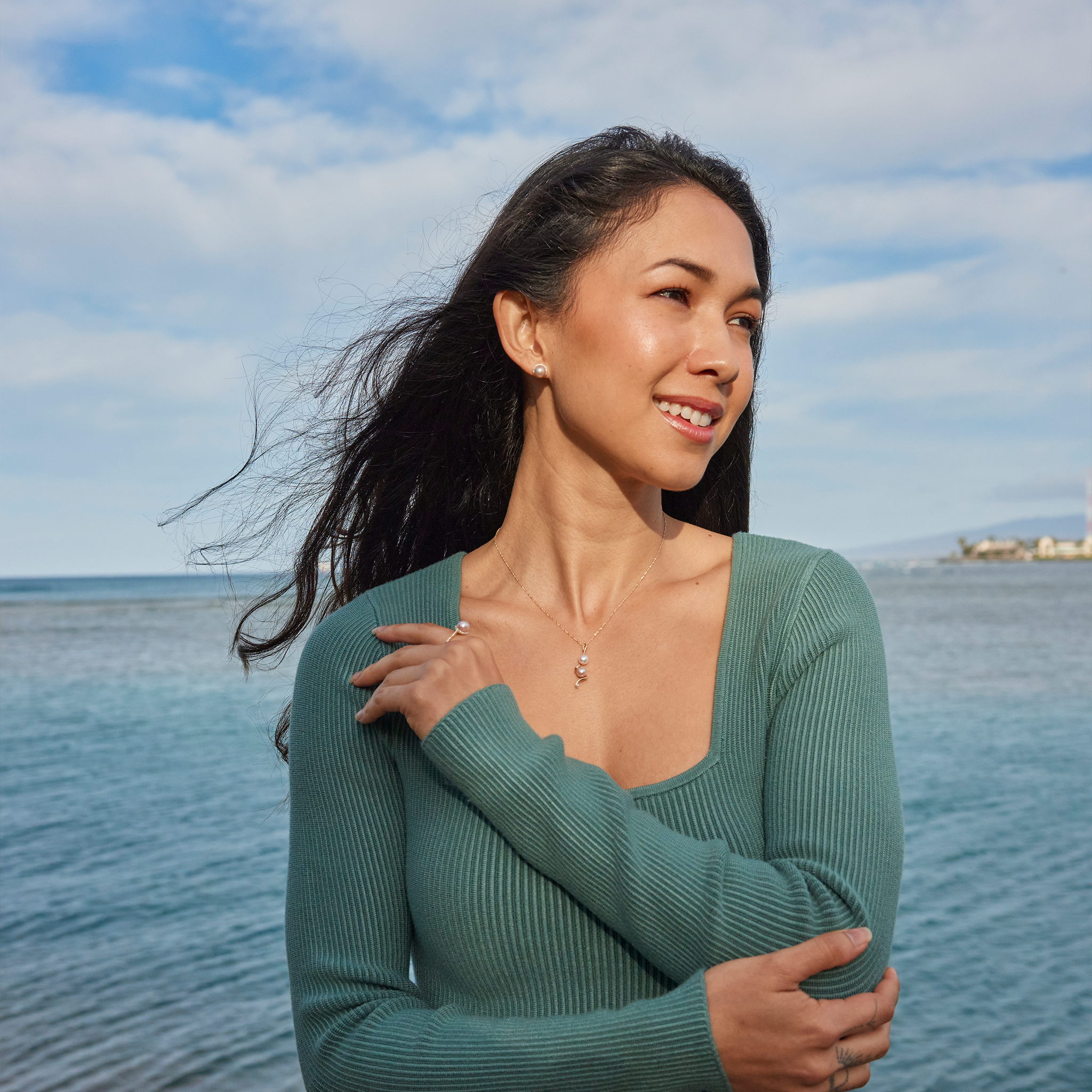Woman by the ocean wearing Pick A Pearl Halo Earrings in Gold with Diamonds and Pink Pearls
