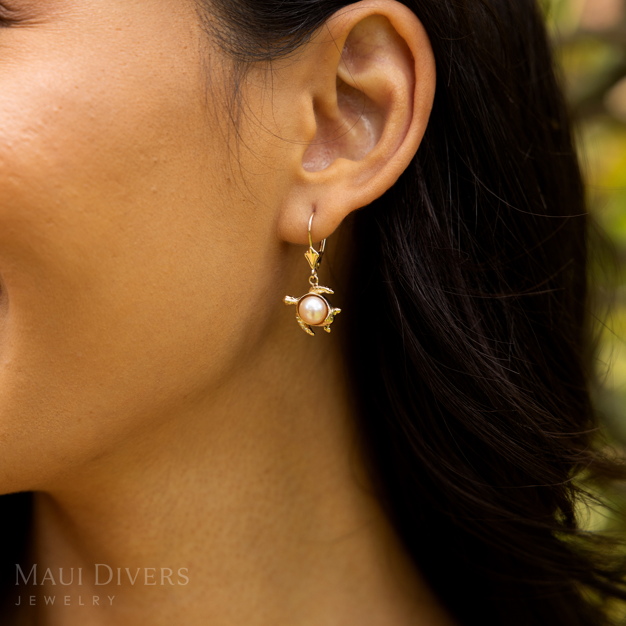 Close up of a woman's ear with a 13mm Pick A Pearl Honu Earrings in Gold with Peach Pearl