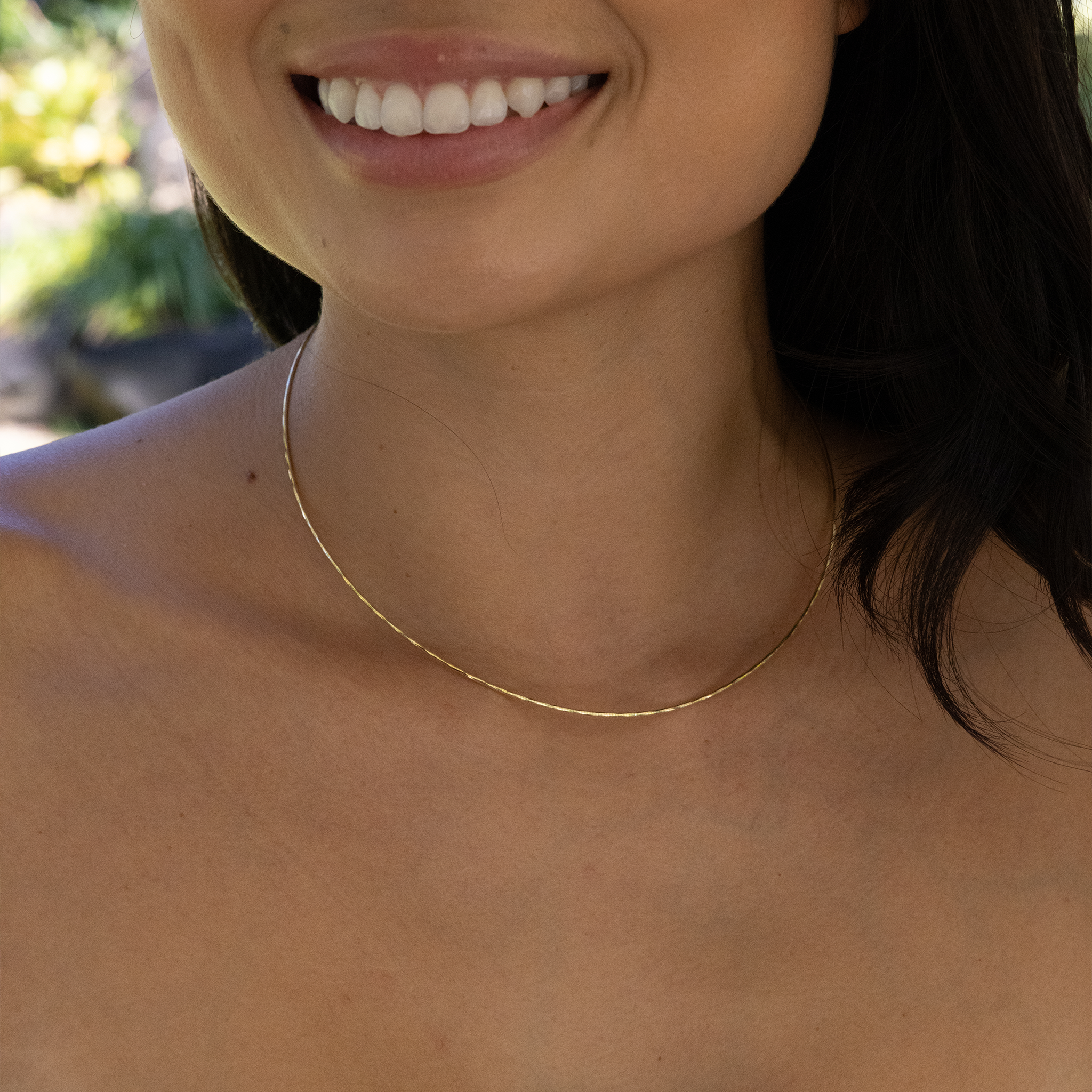 Close up of 1.5mm Round Omega Chain in 14k Yellow Gold on a womanʻs chest