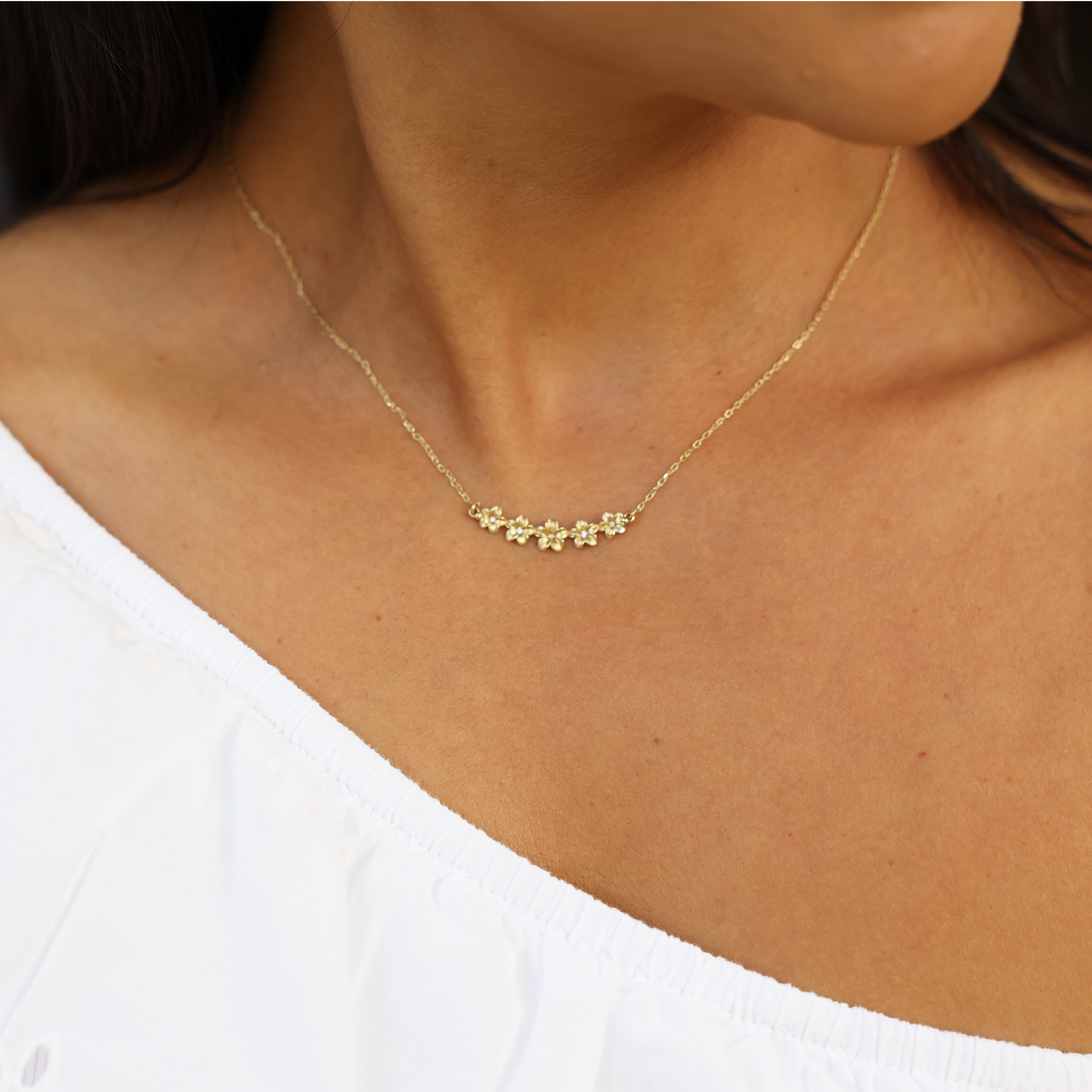 Close up of Plumeria Necklace in Gold with Diamonds on a woman's chest