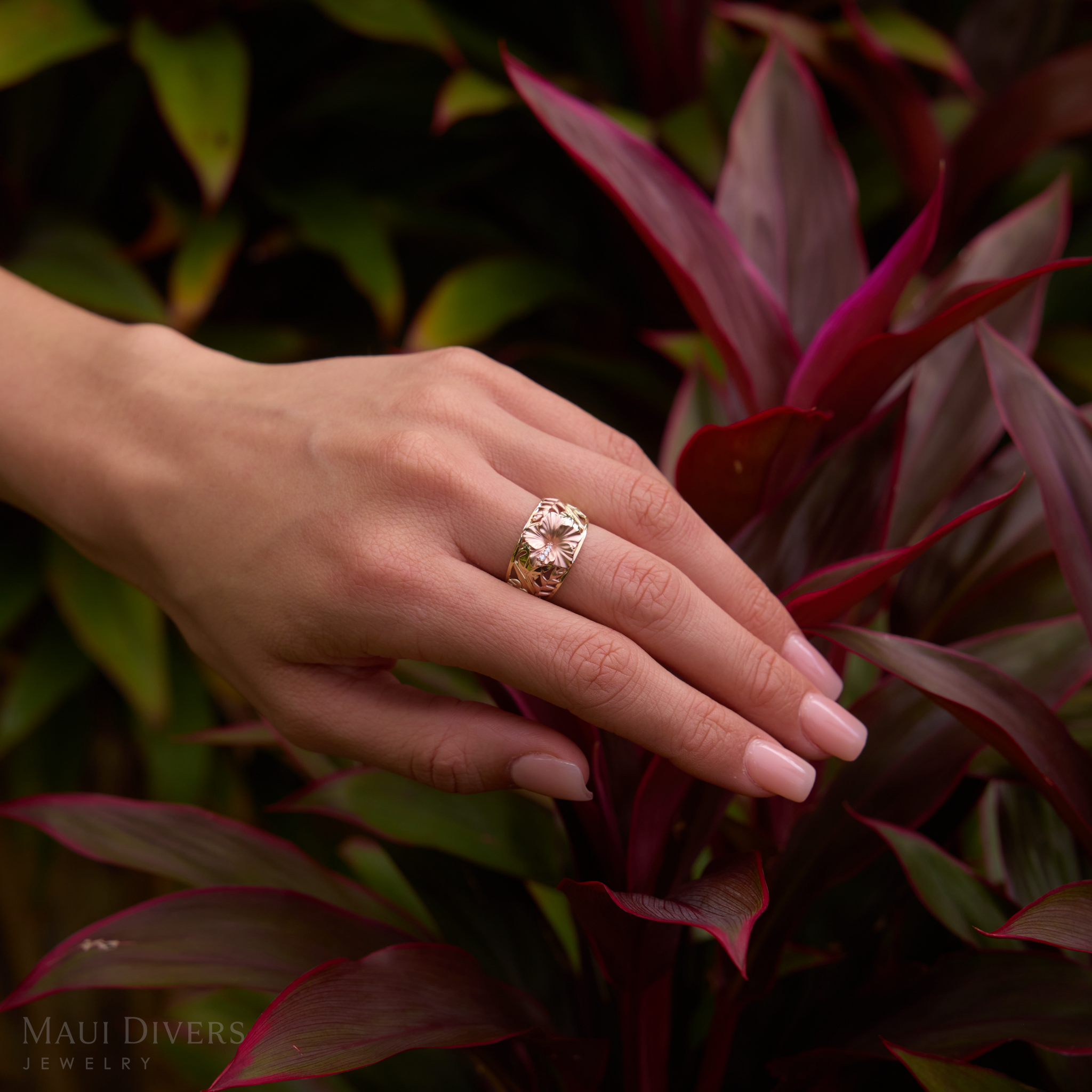 12mm Hawaiian Gardens Hibiscus Ring in 14k Rose, Green, and Yellow Gold with Diamonds on a hand over ti leaves