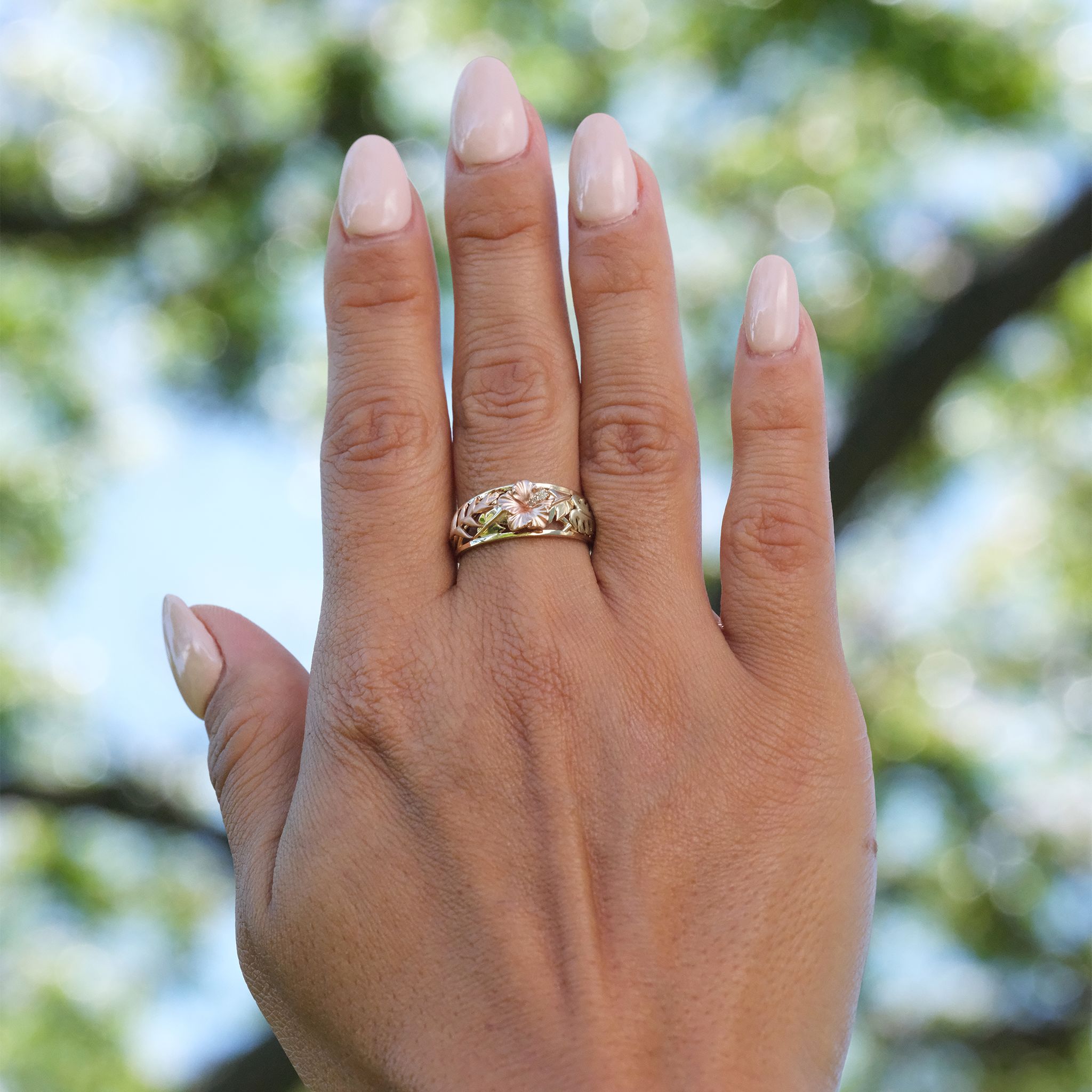 A woman's hand wearing a Hawaiian Gardens Hibiscus Ring in Tri Color Gold with Diamonds - 8mm - Maui Divers Jewelry