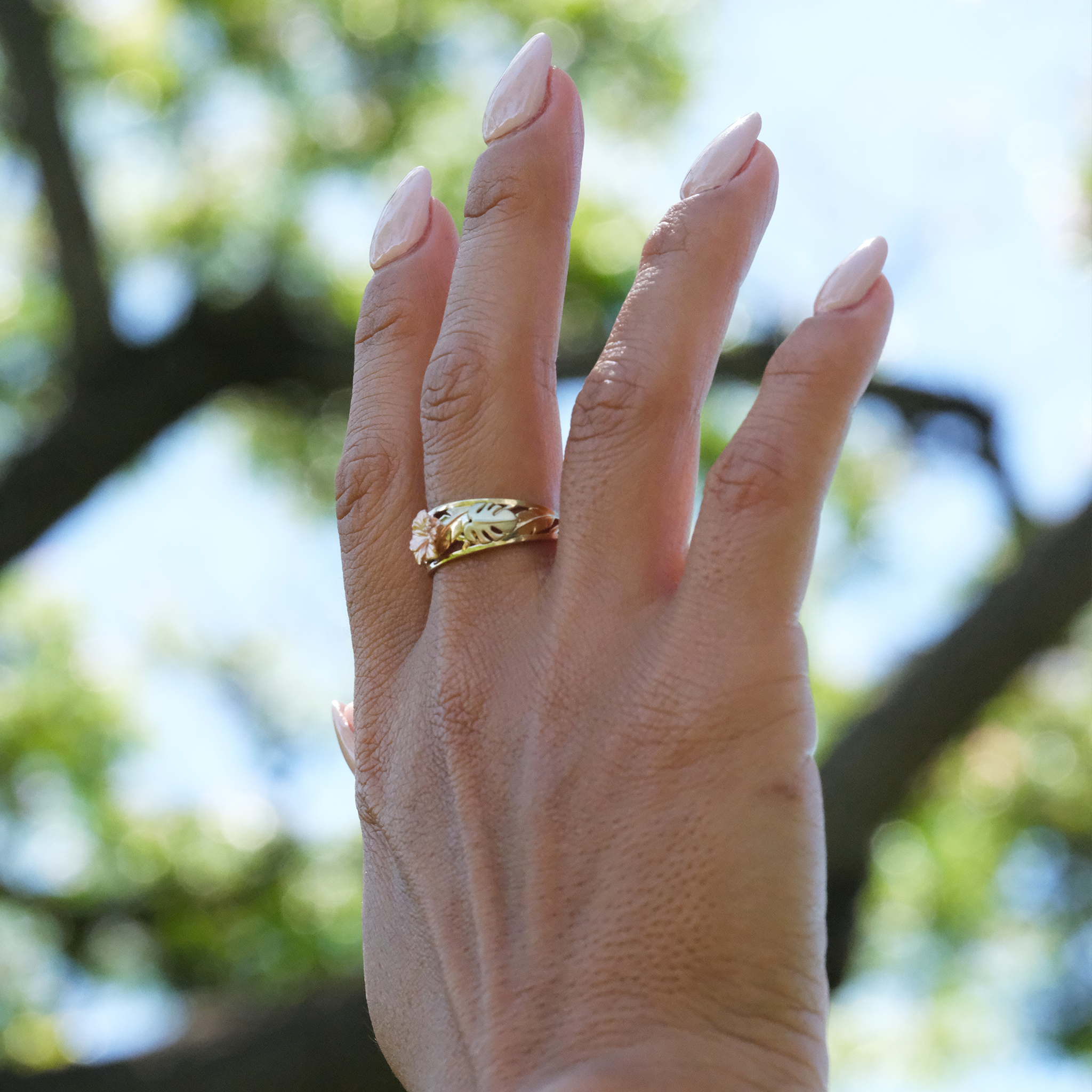 A woman's hand wearing a Hawaiian Gardens Hibiscus Ring in Tri Color Gold with Diamonds - 8mm - Maui Divers Jewelry