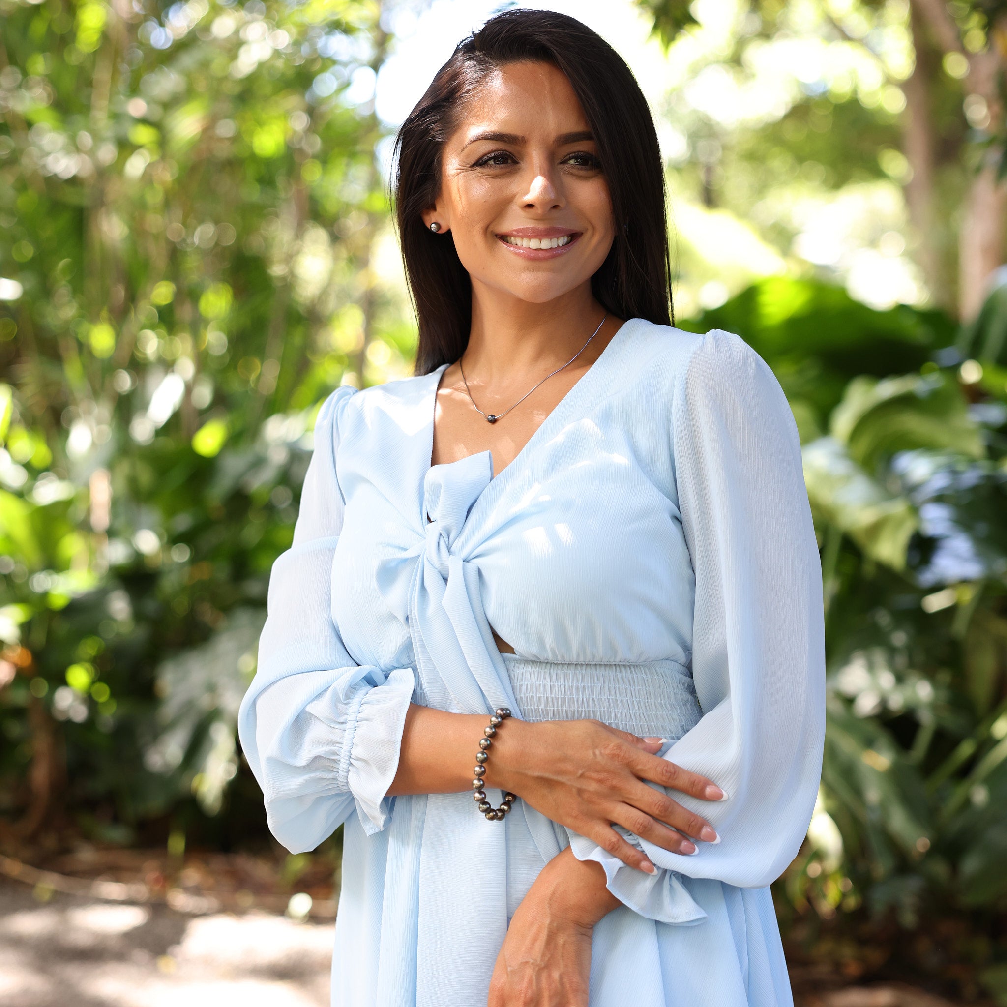 Woman in blue dress wearing a Tahitian Black Pearl Necklace in Sterling Silver in a tropical garden