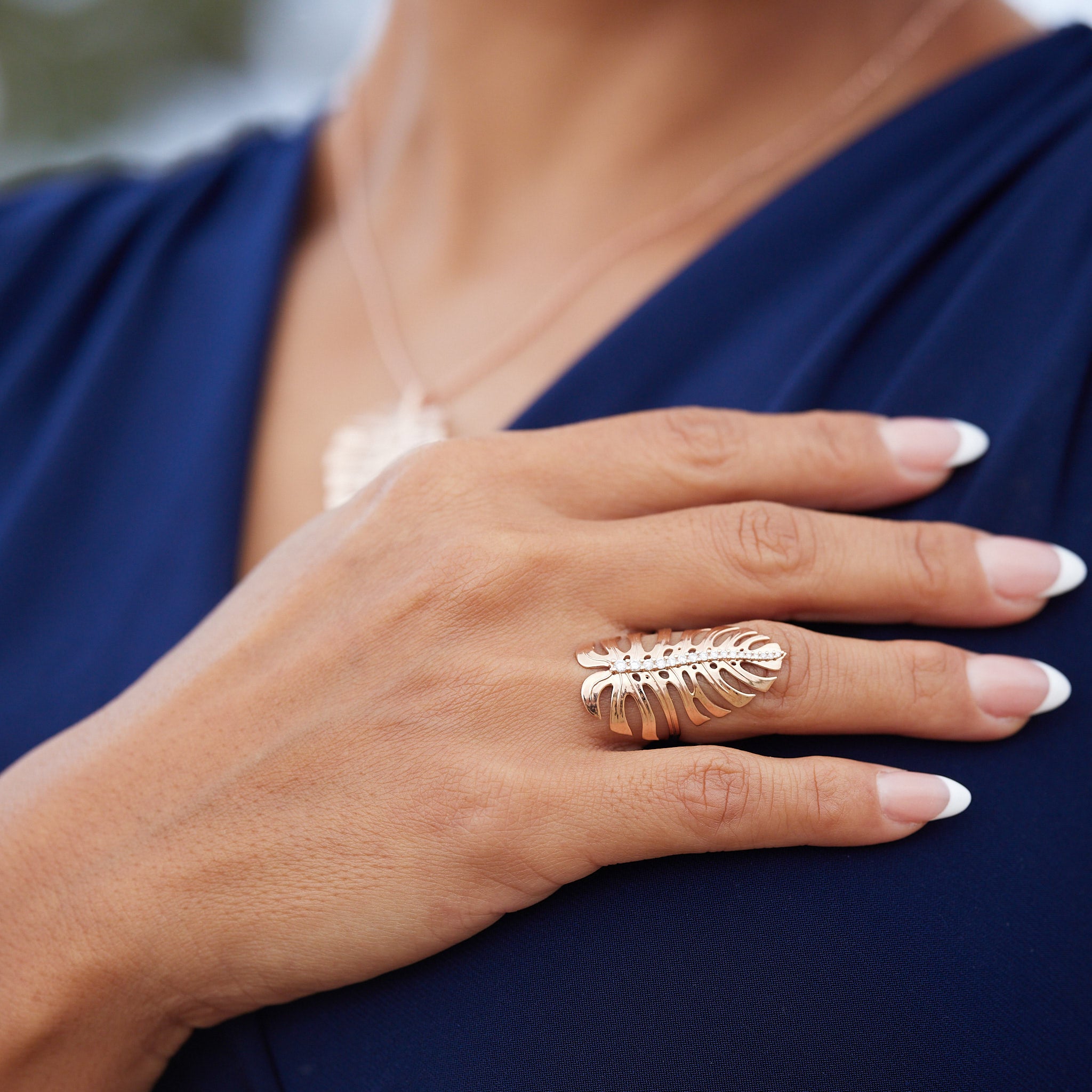 A woman's hand wearing a 32mm Monstera Ring in Rose Gold with Diamonds