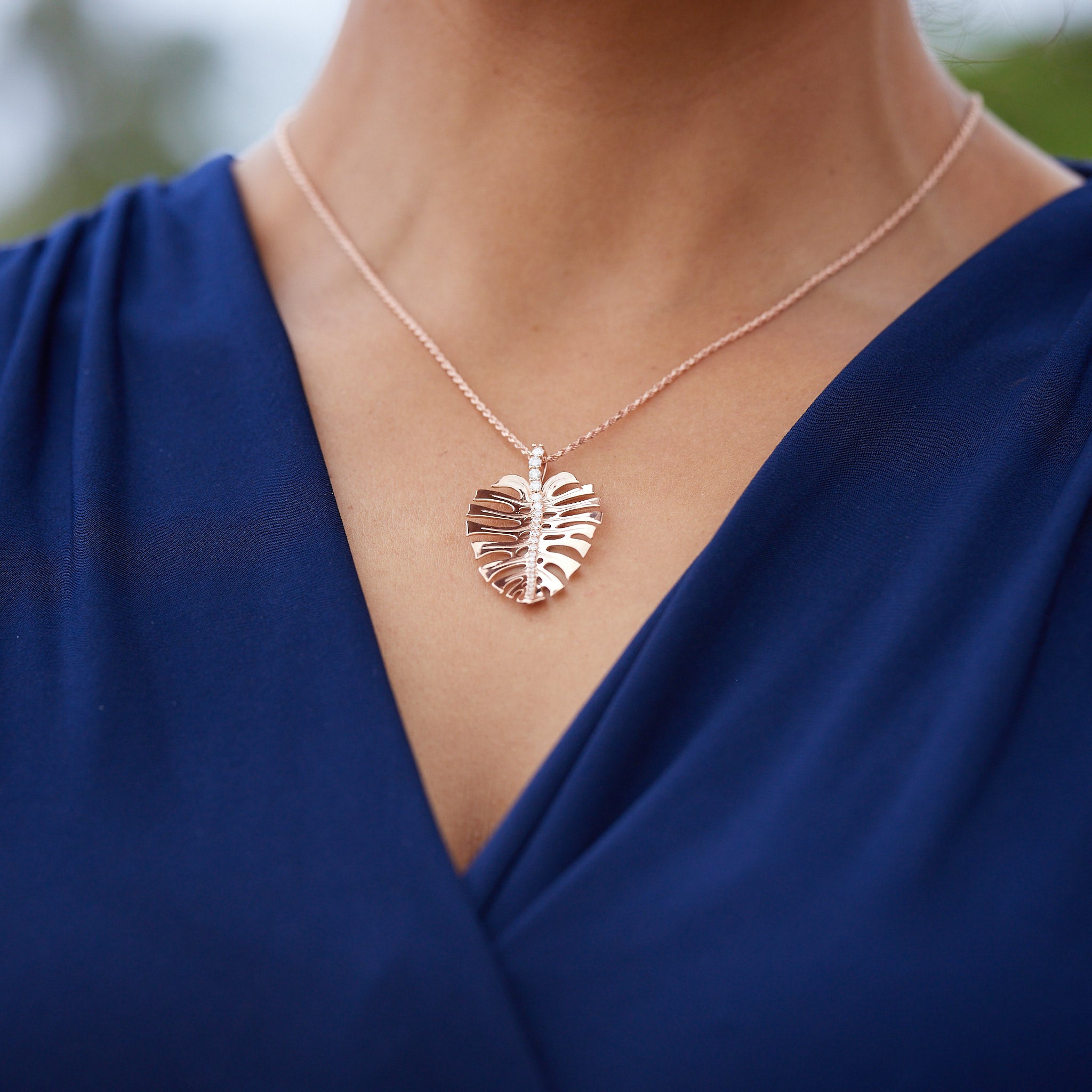 A woman wearing a 18" 1.0mm Flex Rope Chain in Rose Gold with a Monstera Pendant outdoors