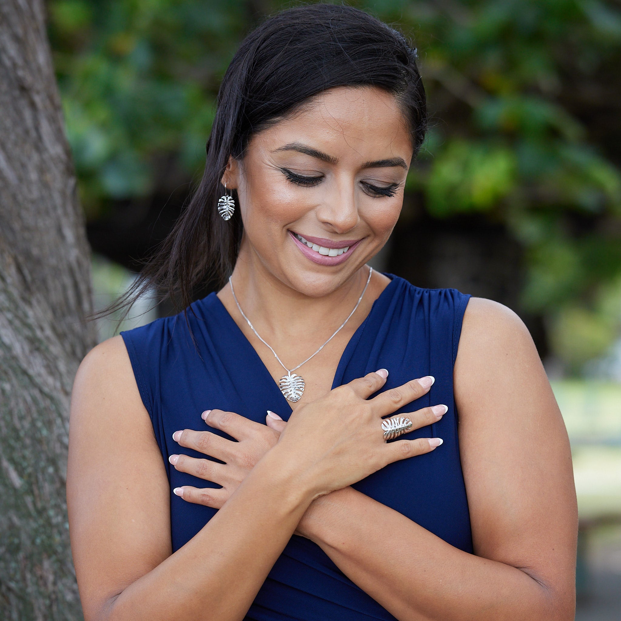A woman in a park wearing a Monstera Pendant in White Gold with matching earrings and ring