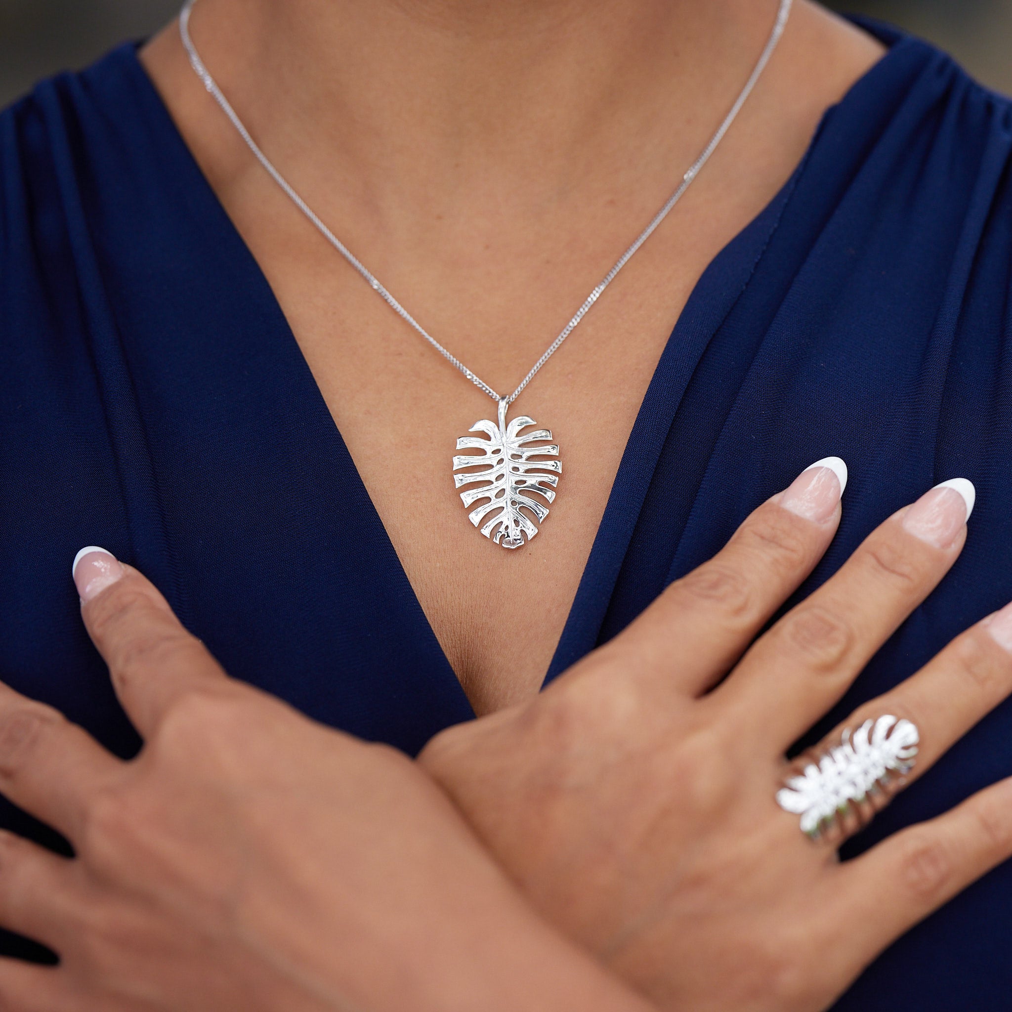 A woman's chest with a Monstera Pendant in White Gold and matching ring